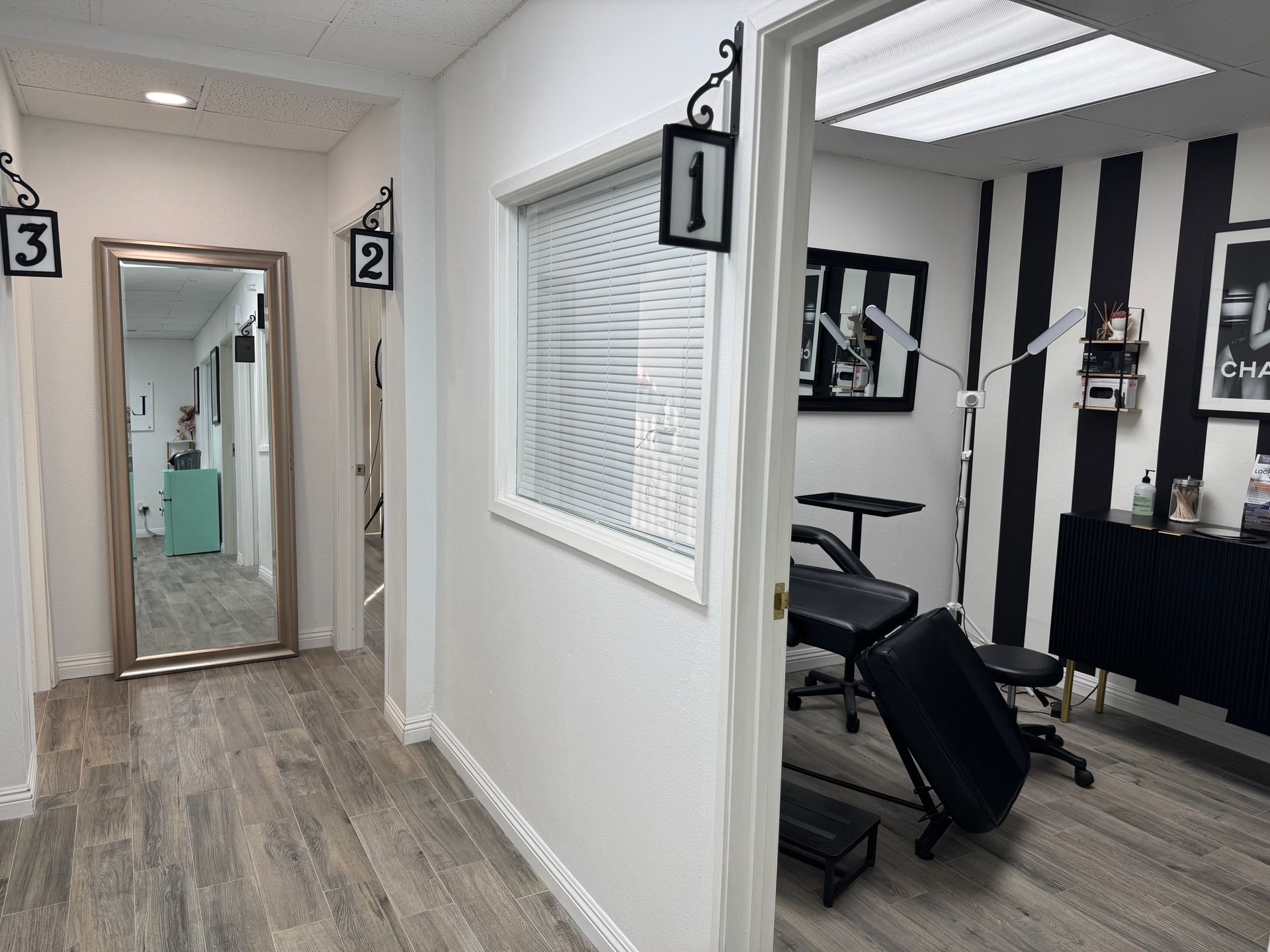 A hallway with a mirror and a black and white striped wall.