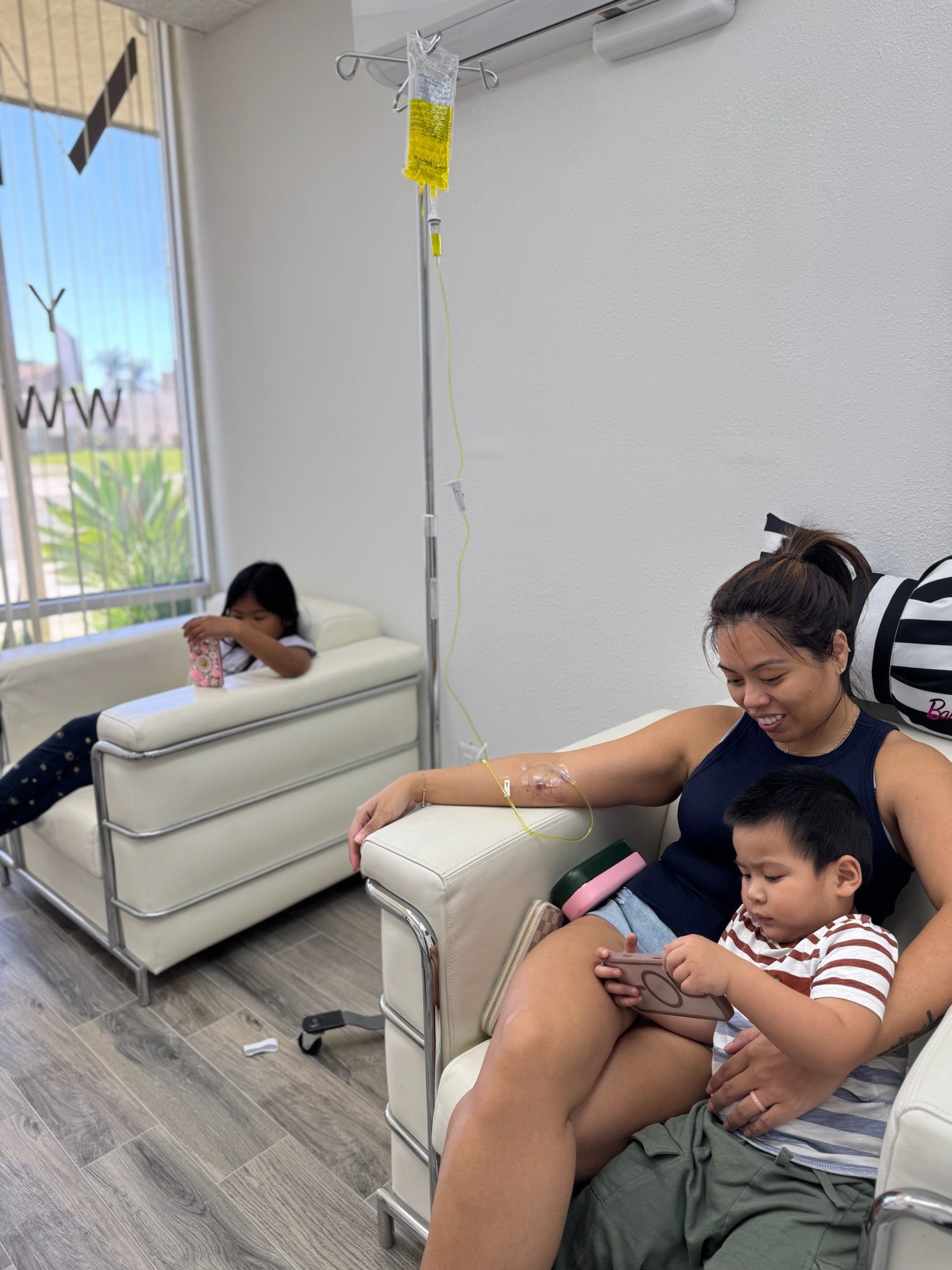 Woman and two children receiving IV therapy, indoors.