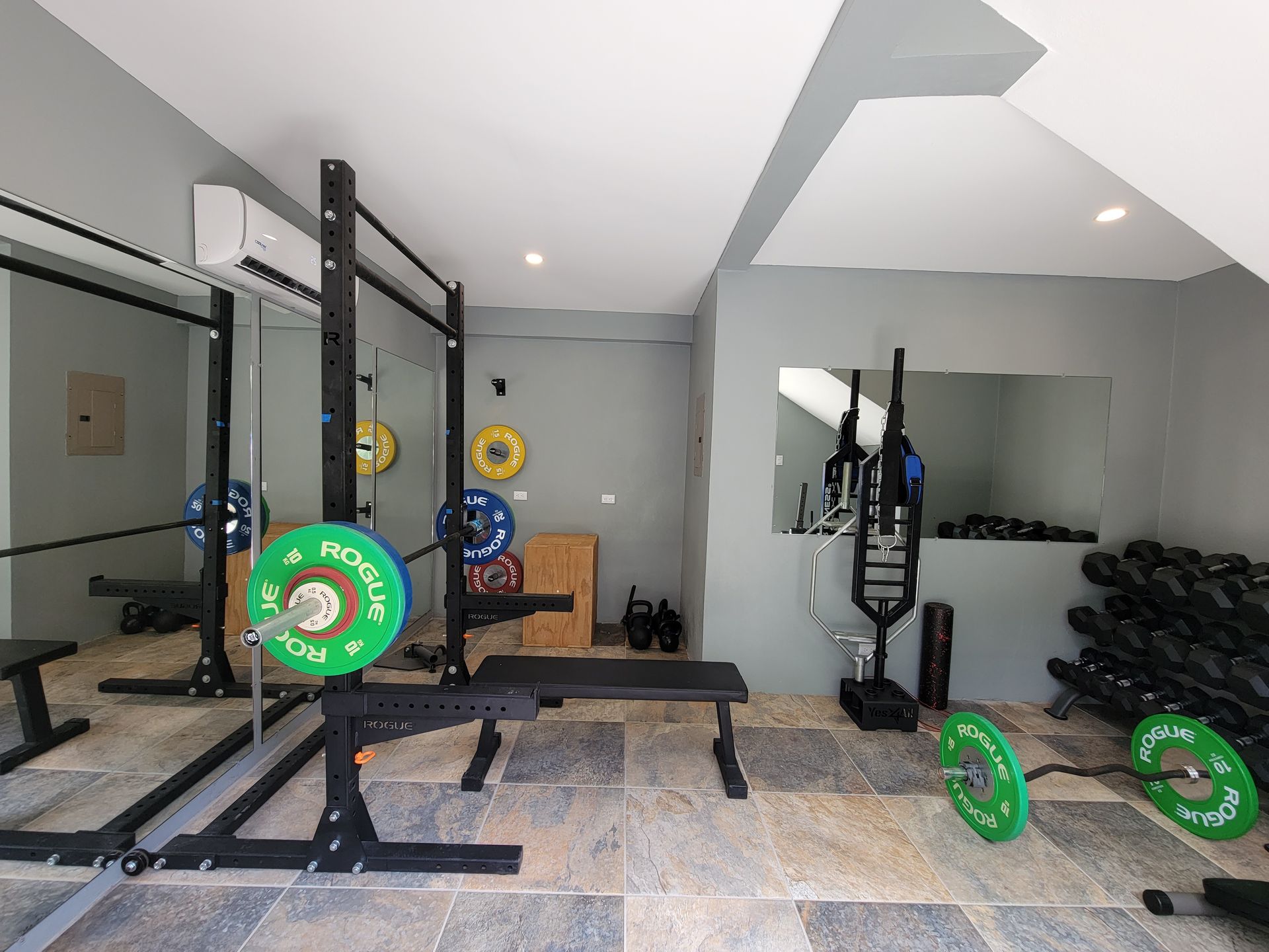 A gym with a lot of weights and a bench.