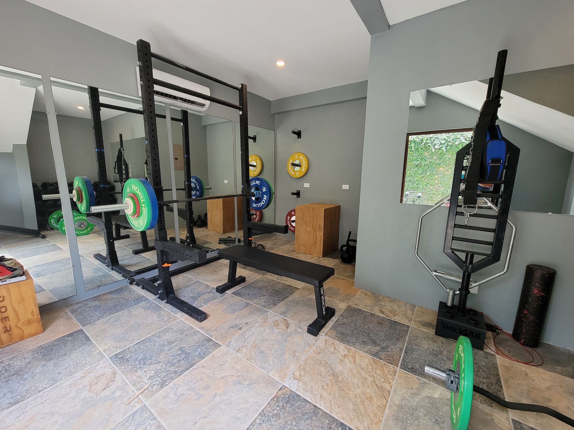 A gym with a lot of equipment and a bench.