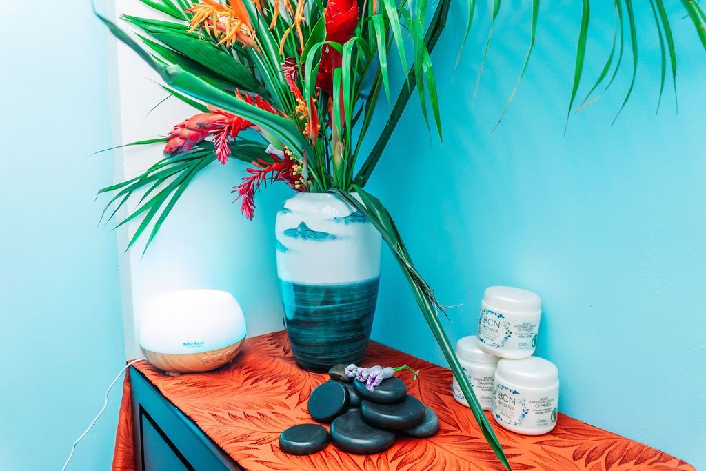 A table with a vase of flowers and hot rocks on it.