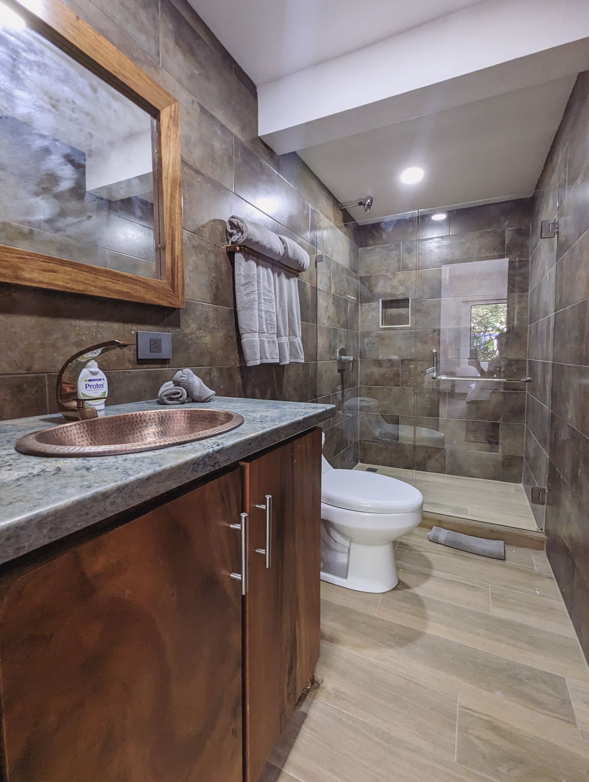 A bathroom with a sink , toilet , mirror and walk in shower.