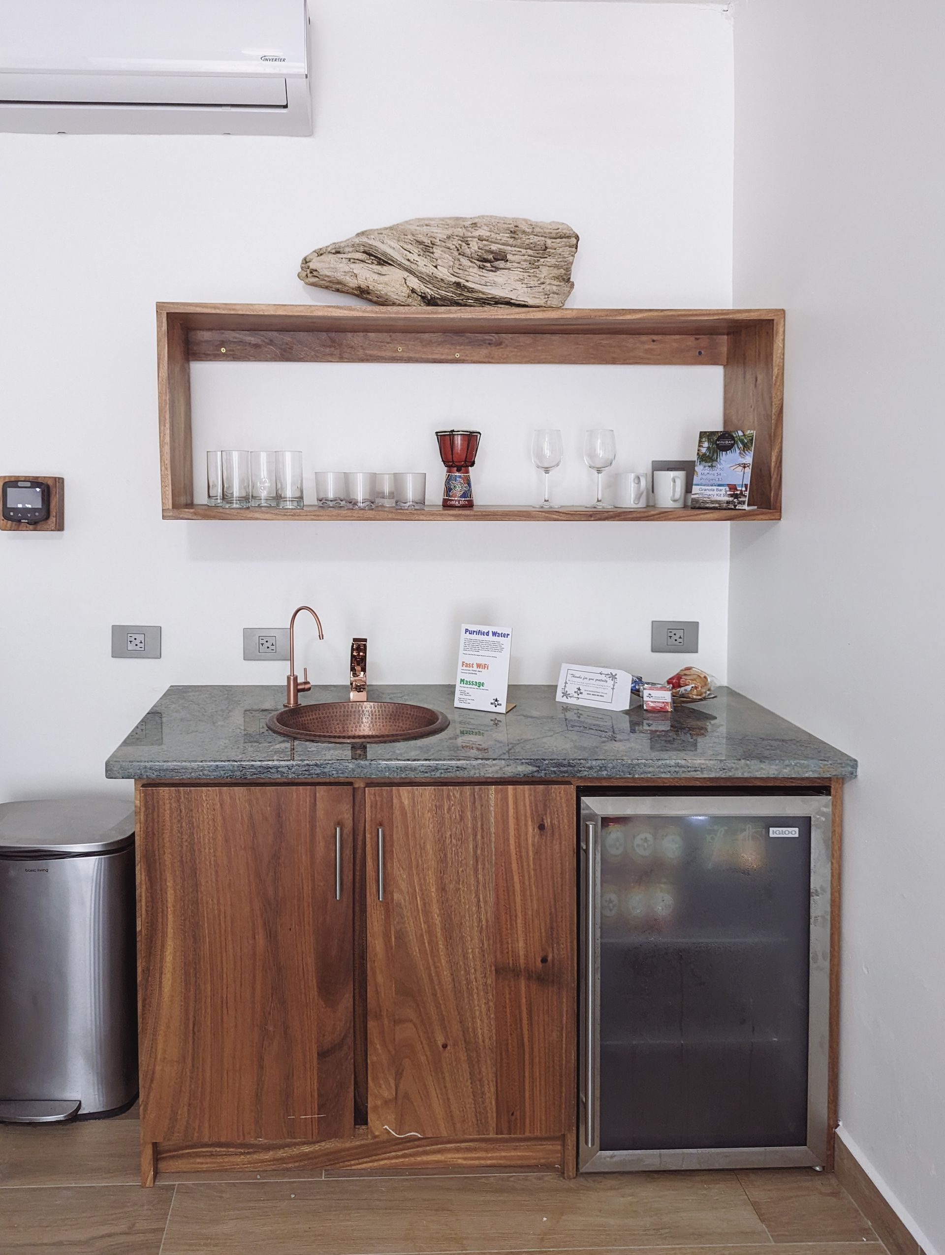 A kitchen with a sink , refrigerator , and shelves.