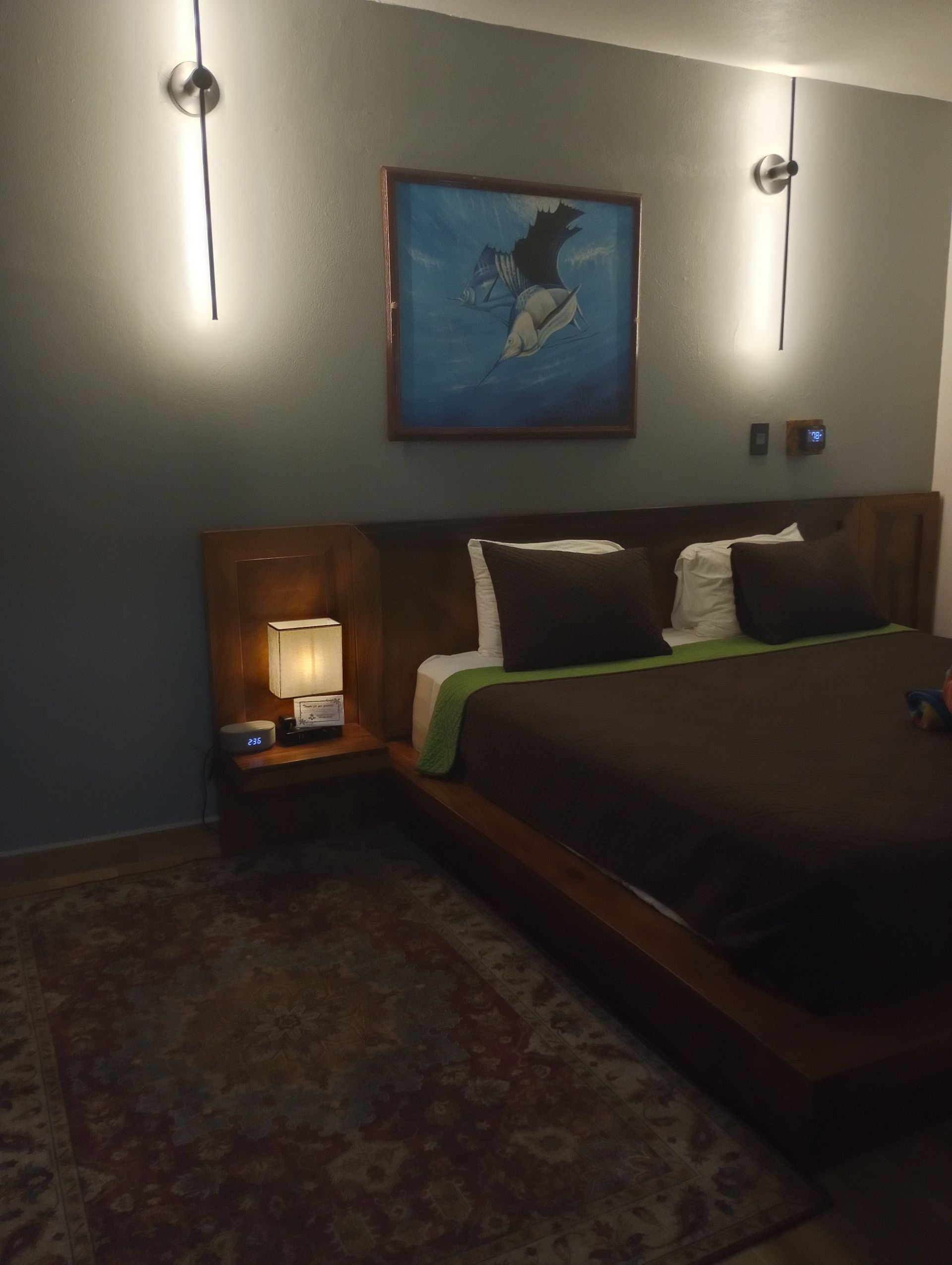 A bedroom with a large bed and a painting on the wall