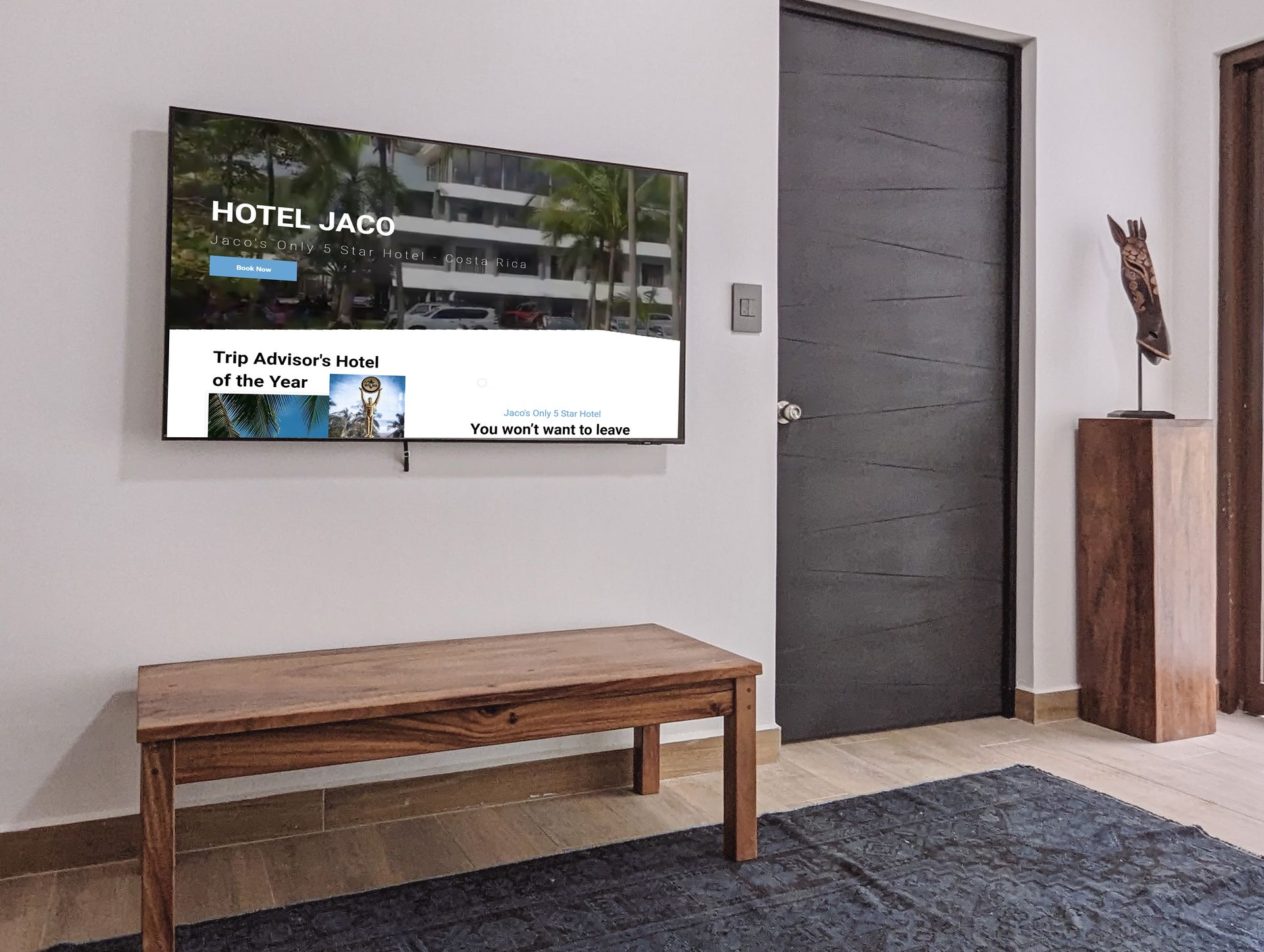 A living room with a wooden bench and a flat screen tv on the wall.