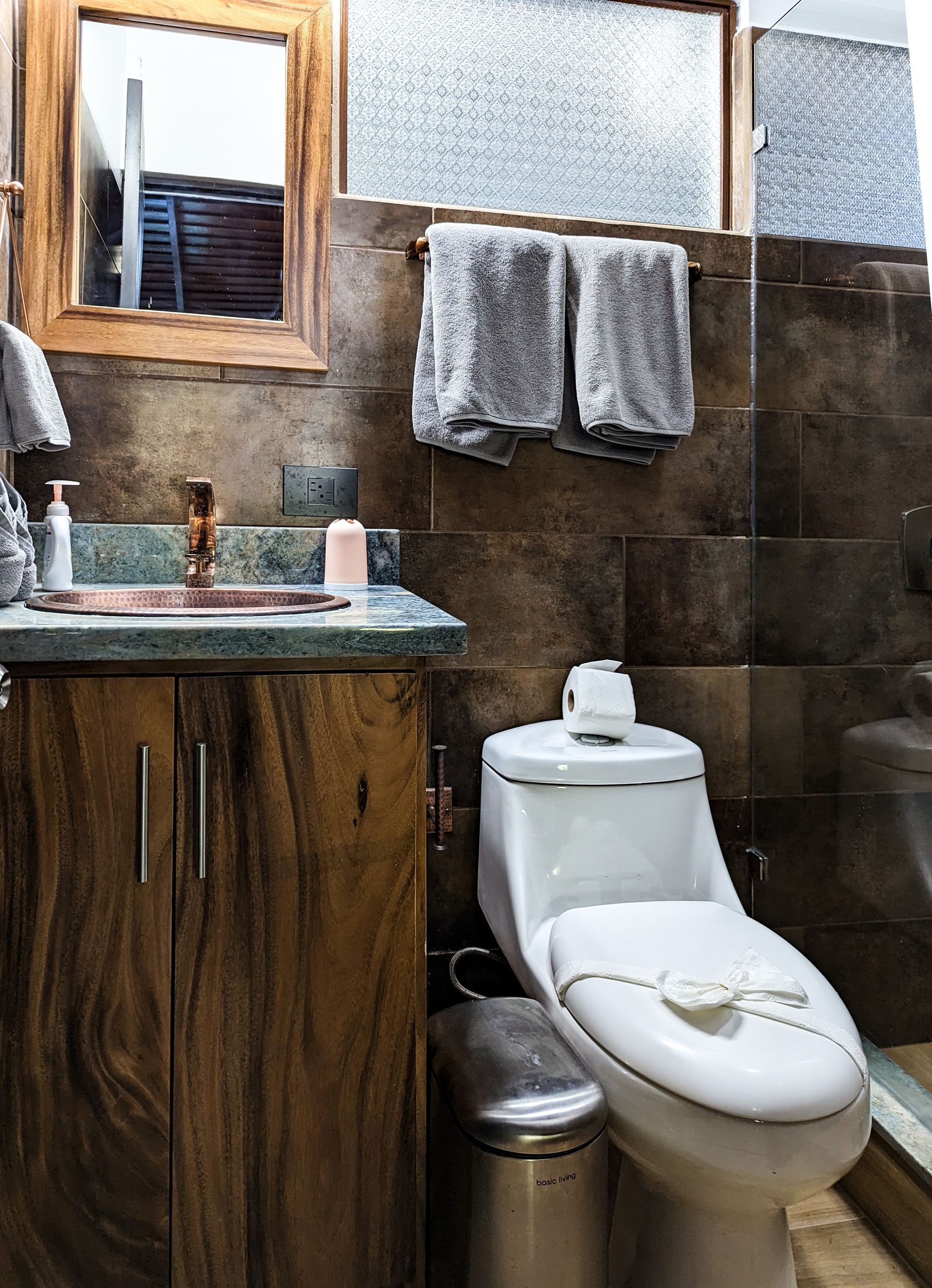 A bathroom with a toilet , sink and mirror.