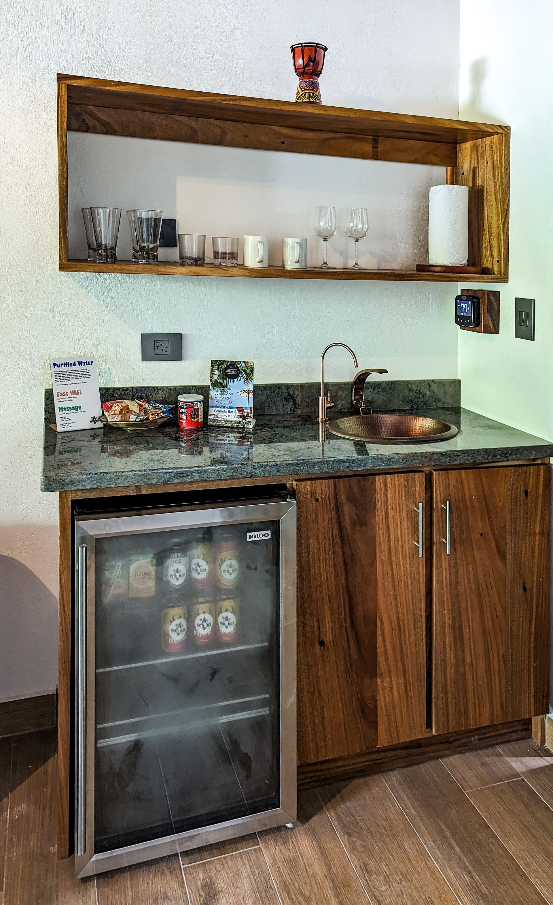 A kitchen with wooden cabinets , a sink , a refrigerator and a shelf.