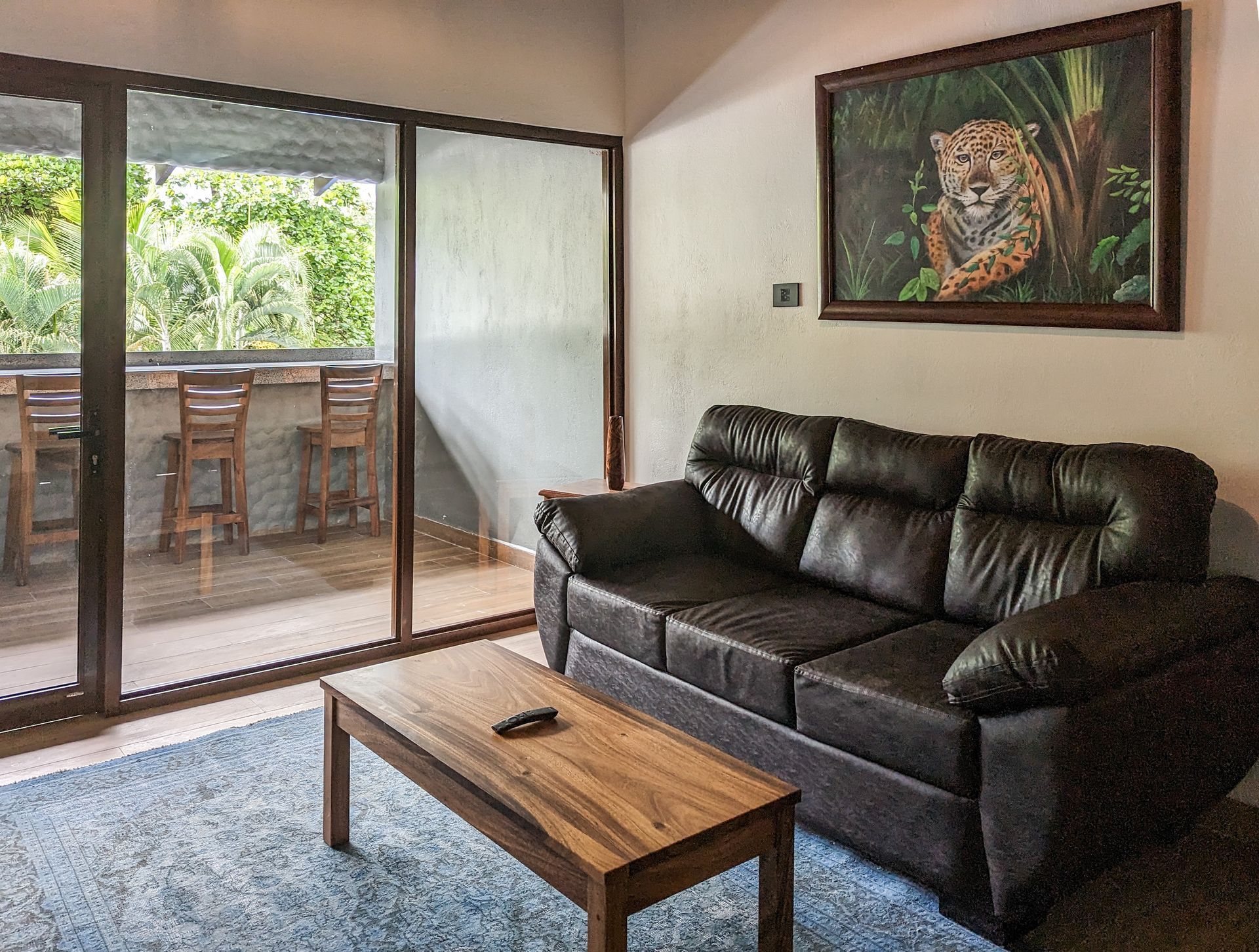 A living room with a couch , coffee table , and a painting on the wall.