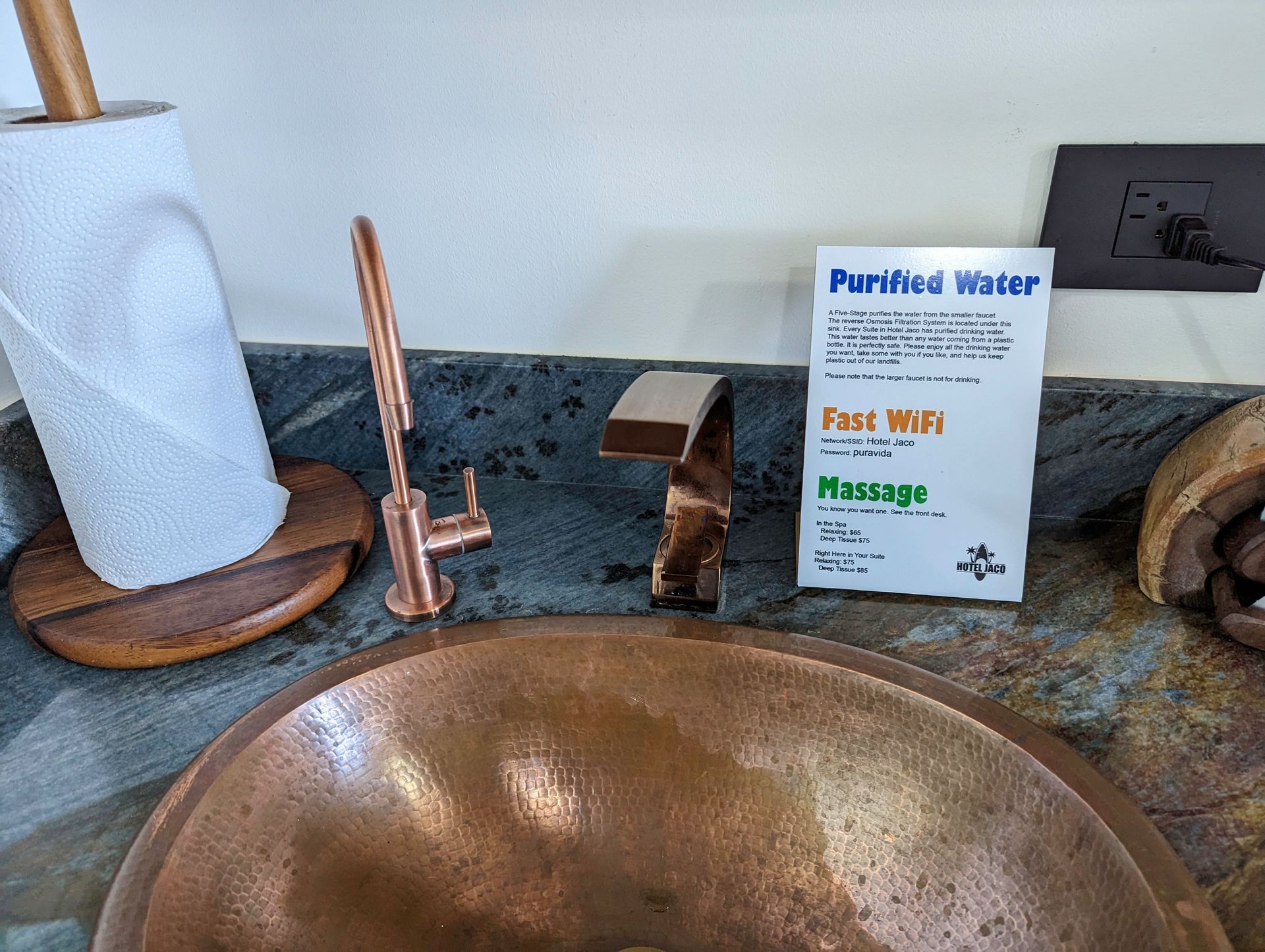 A bathroom sink with a paper towel holder and a sign that says purified water
