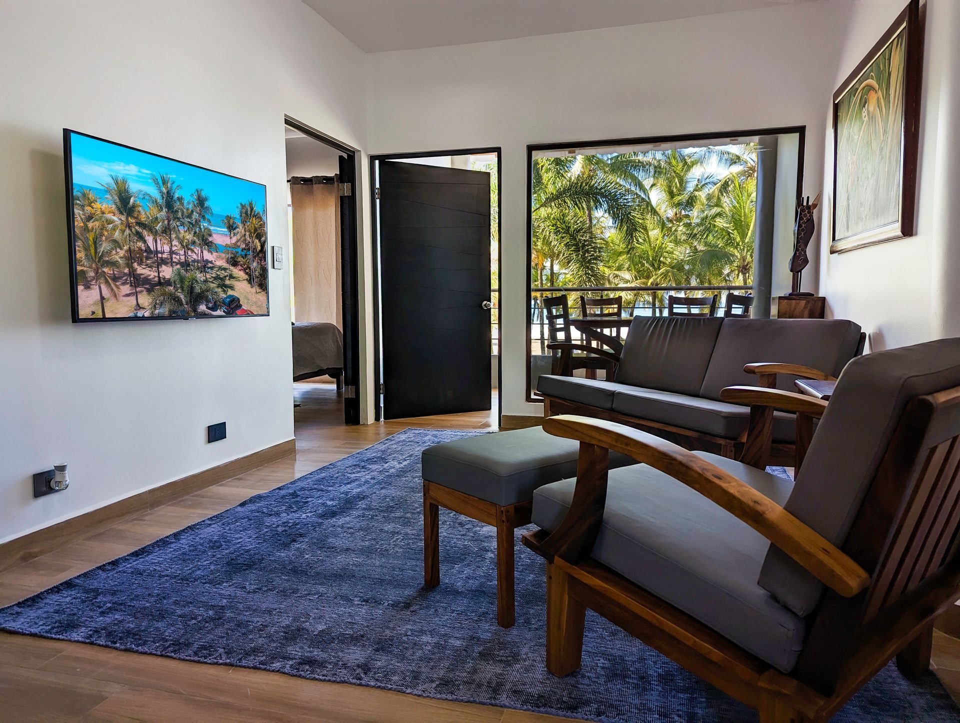 A living room with a couch , chairs , and a flat screen tv.
