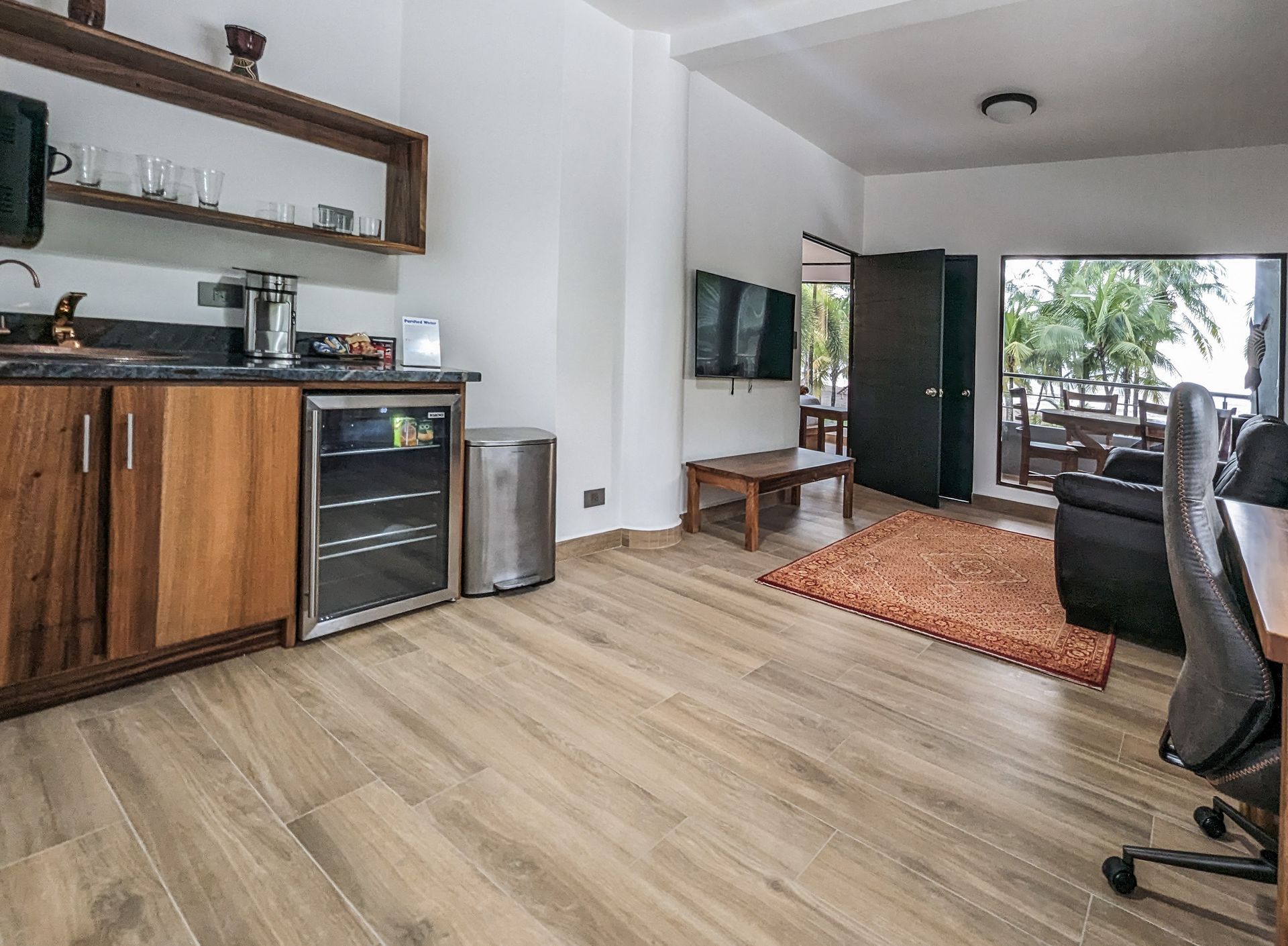 A living room with hardwood floors and a refrigerator.