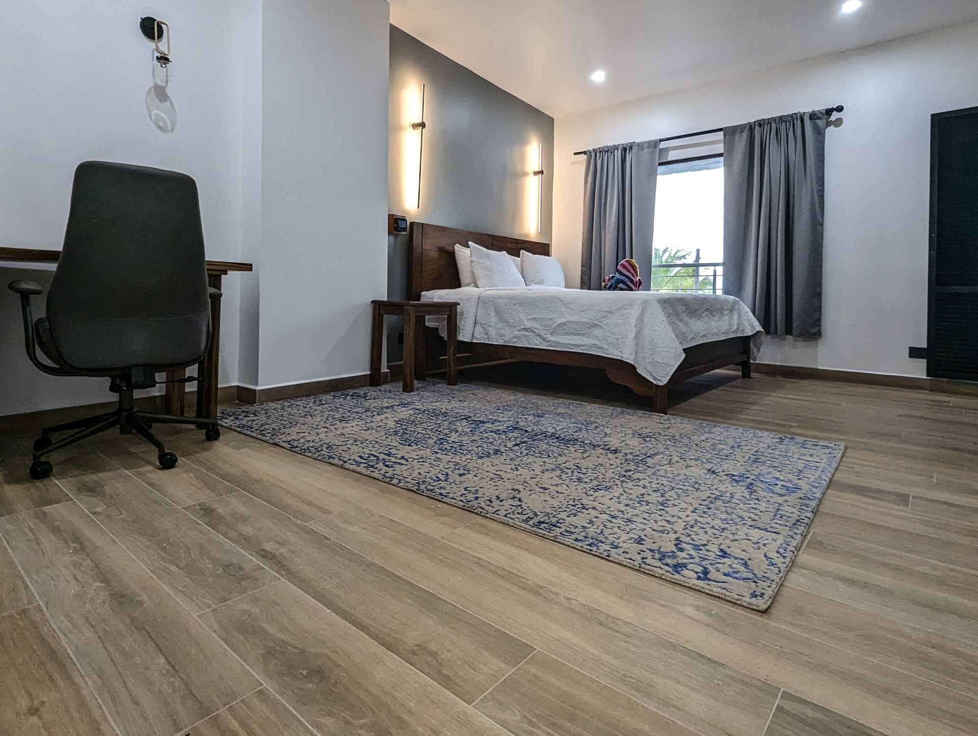 A bedroom with a large bed , desk , chair and rug.