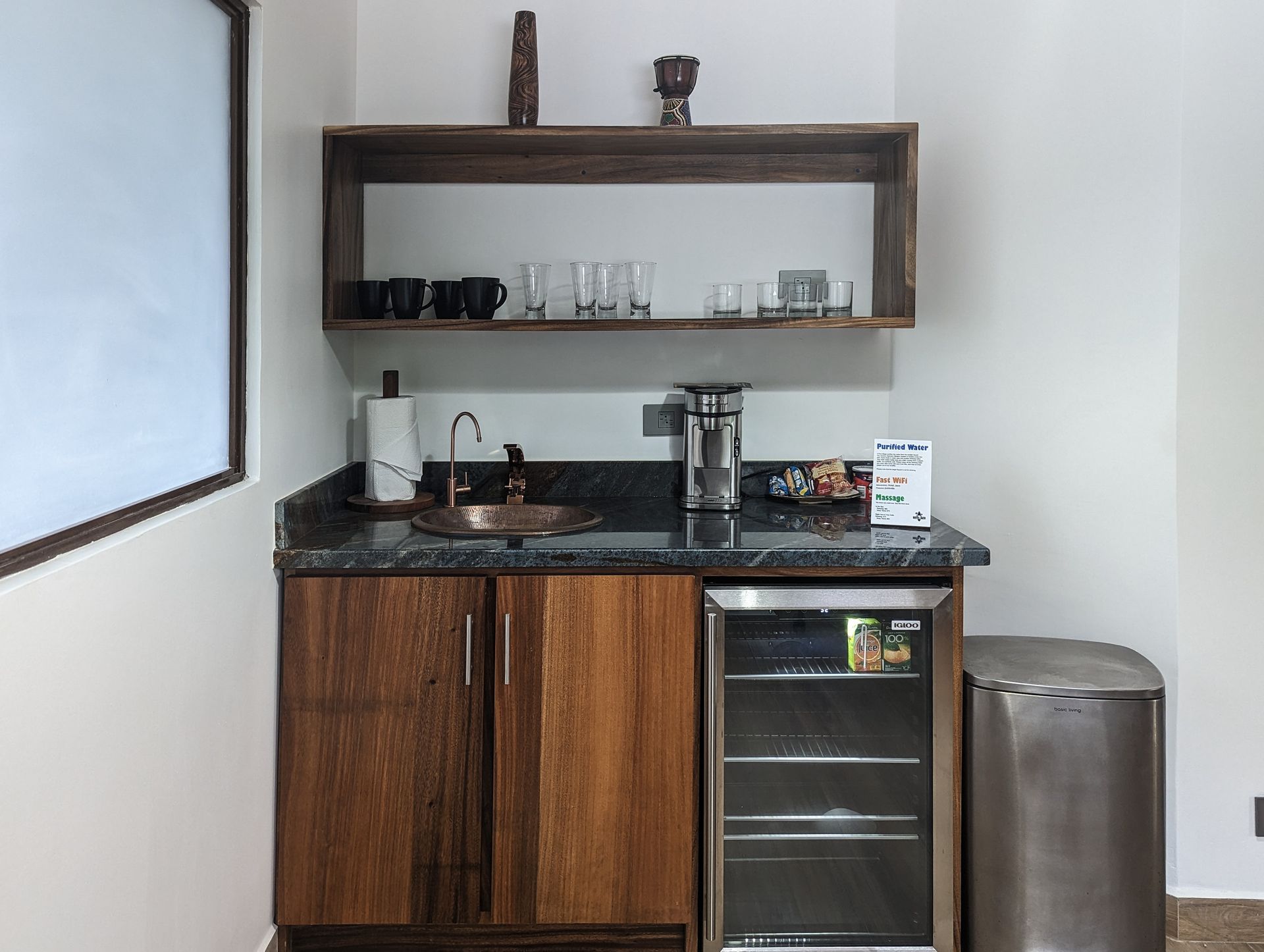 A small kitchen with a sink a refrigerator and a trash can