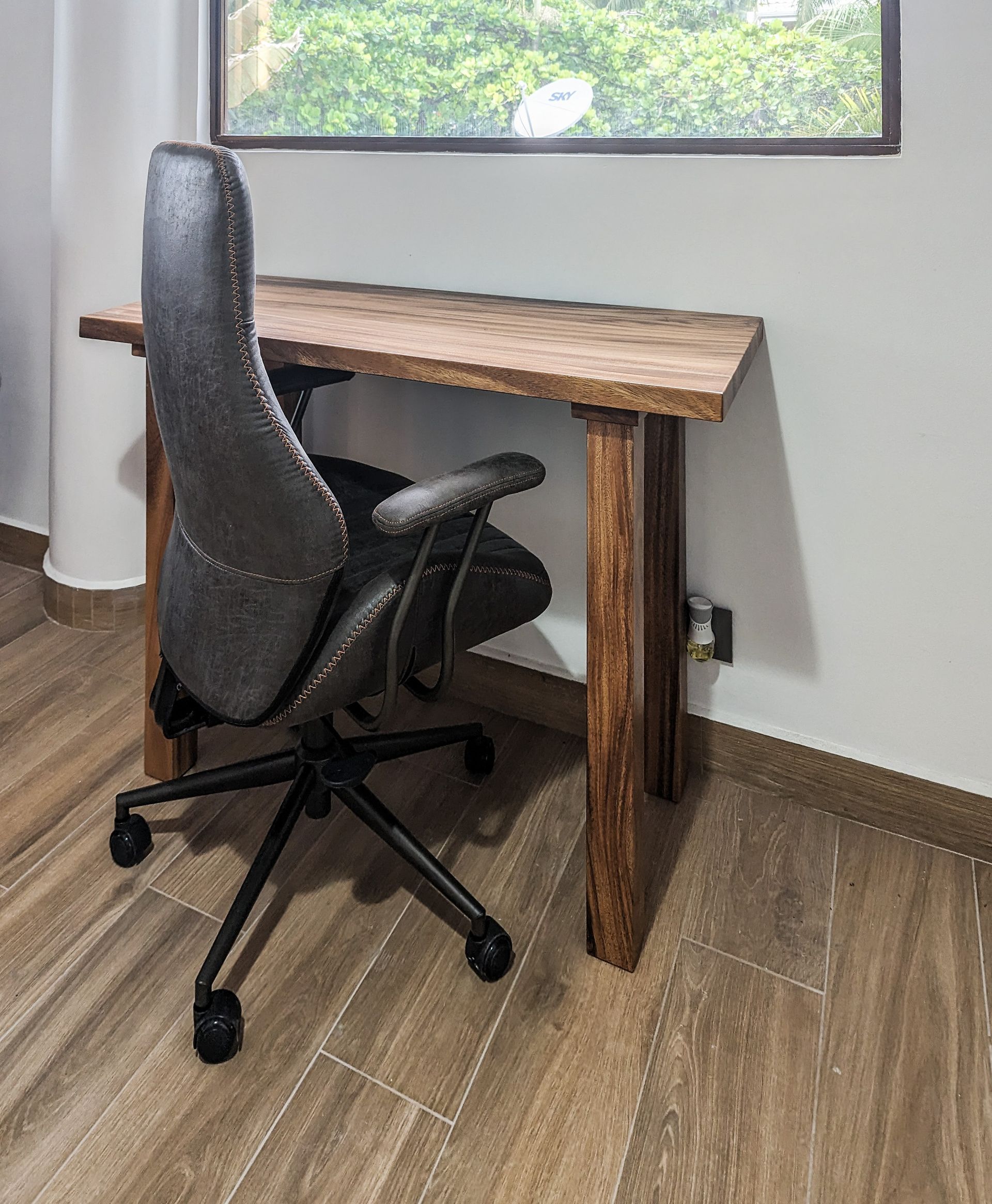 A chair is sitting next to a wooden desk in a room.