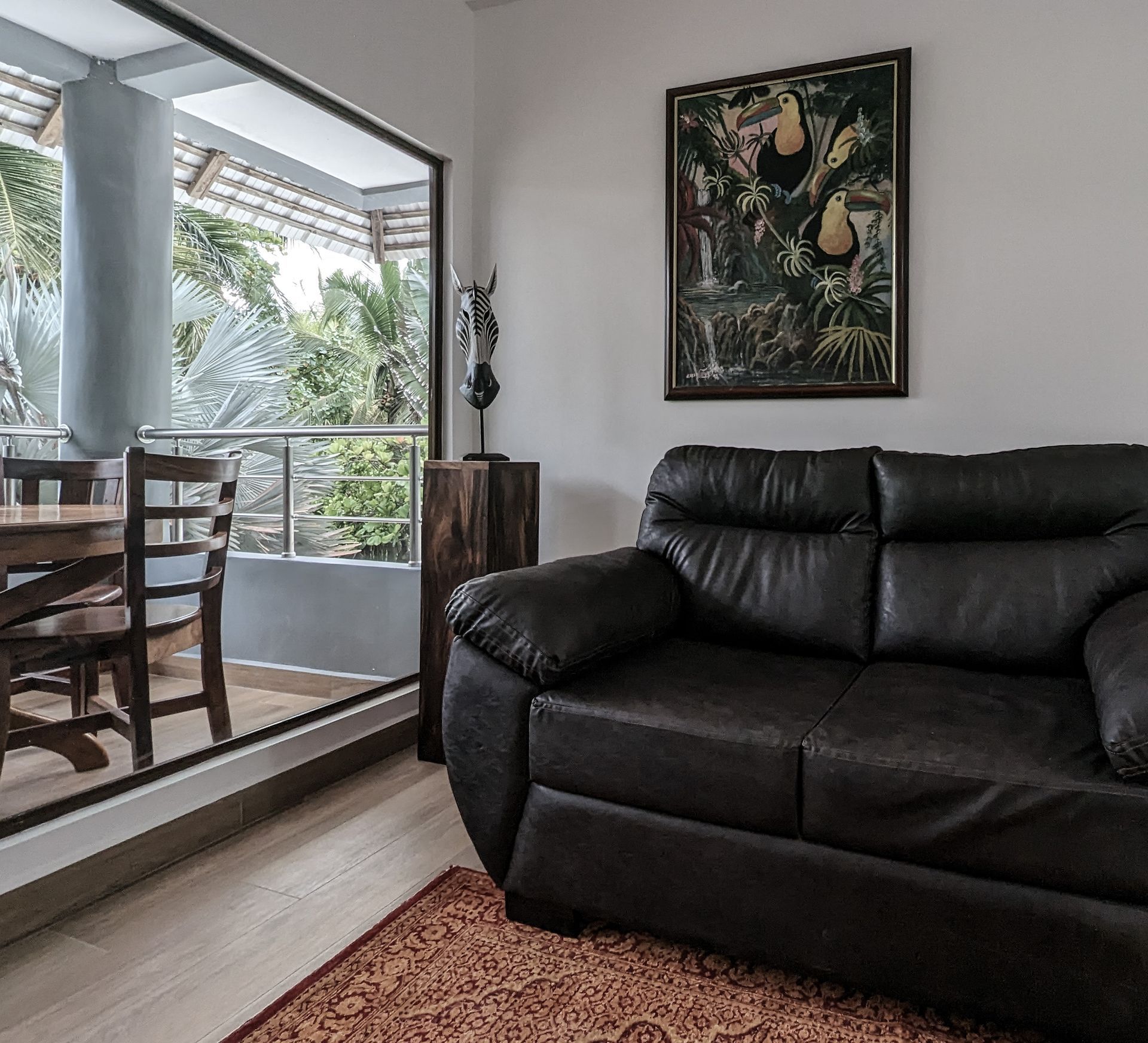 A living room with a black couch and a picture on the wall