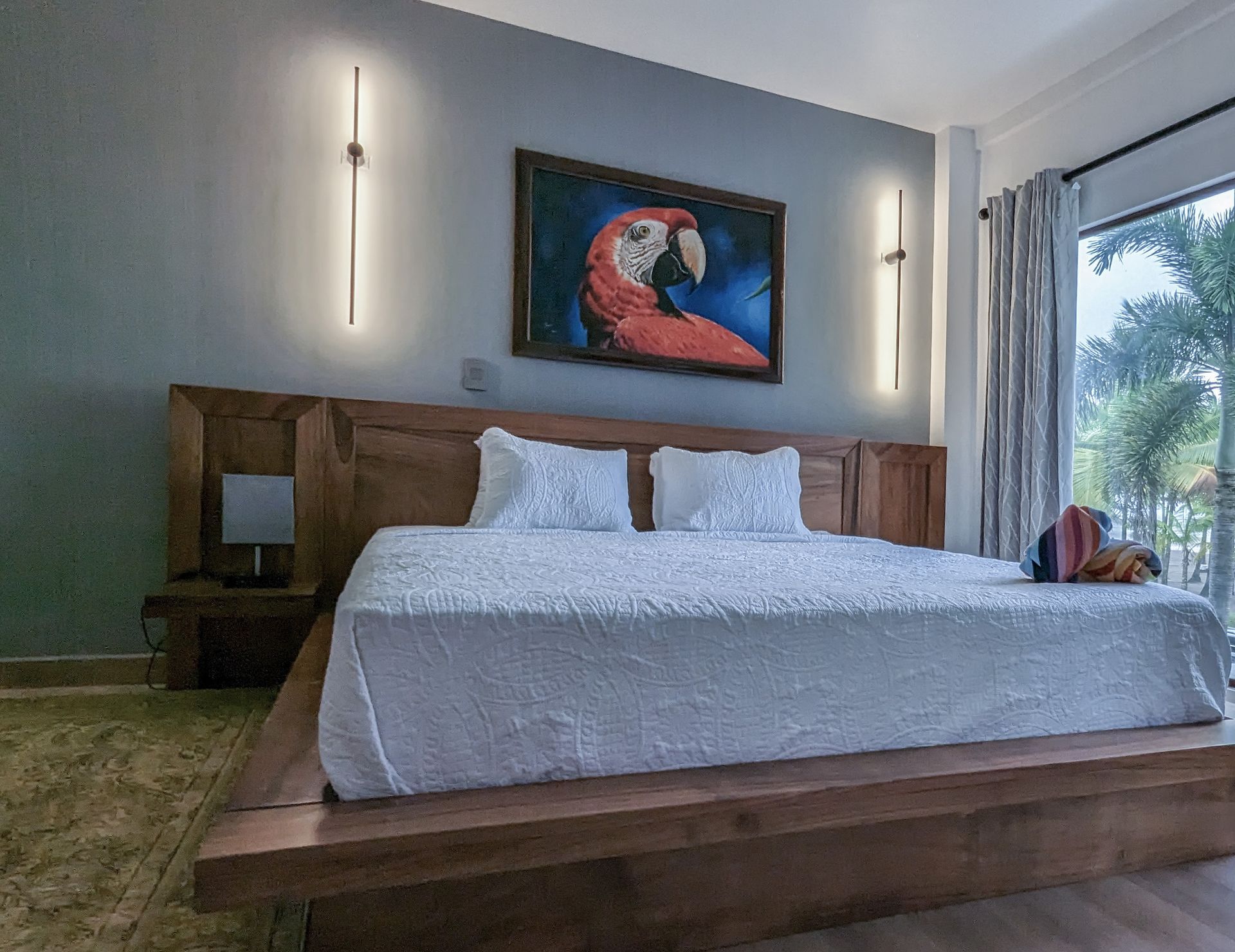 There is a painting of a parrot on the wall above the bed.