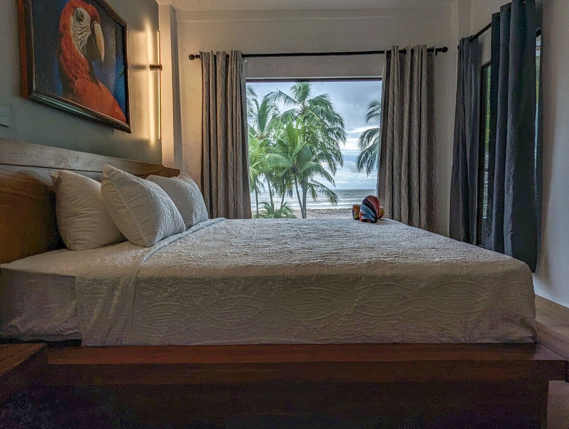 A bedroom with a bed and a window with a view of the ocean.