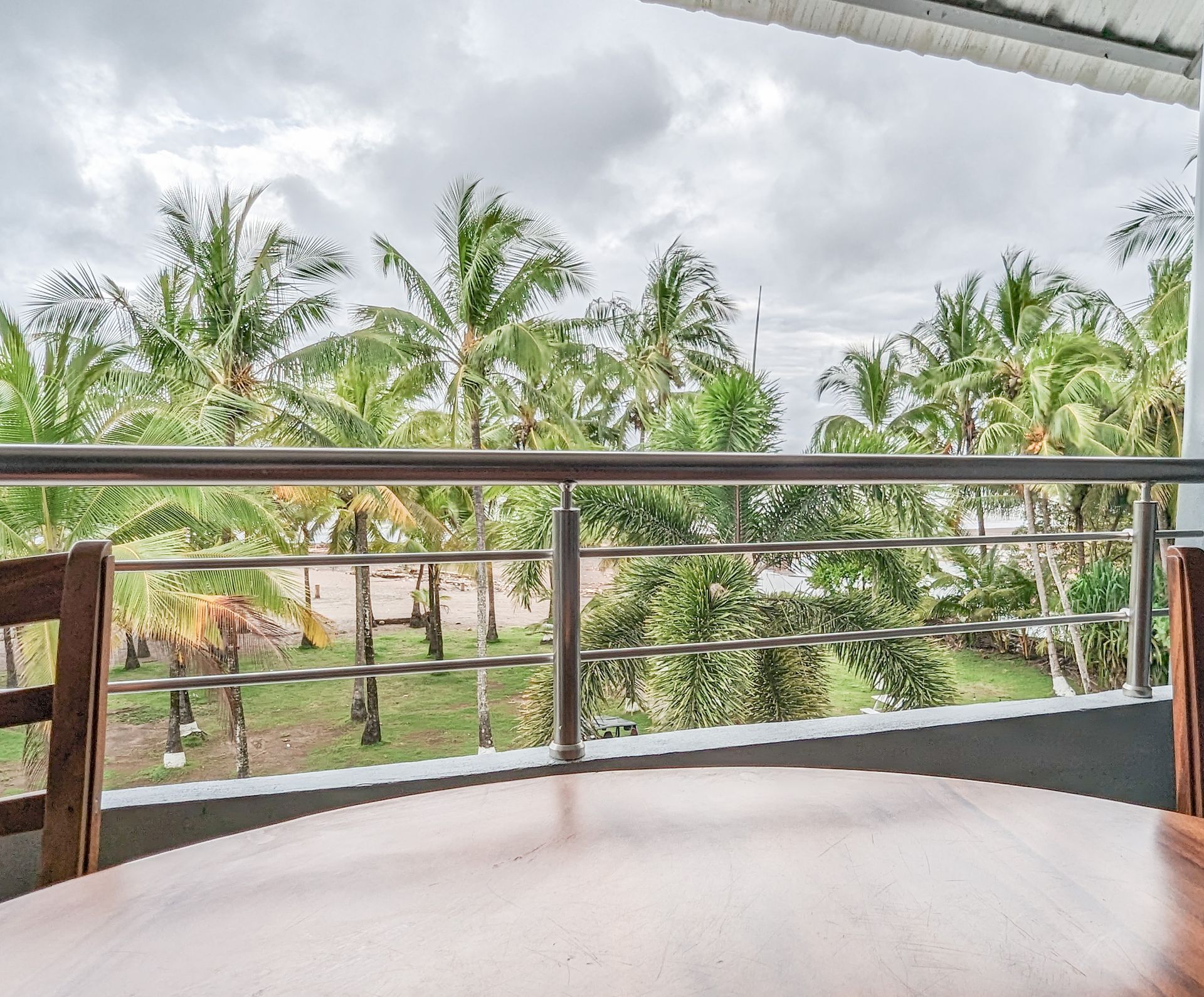 A balcony with a table and chairs and a view of palm trees.