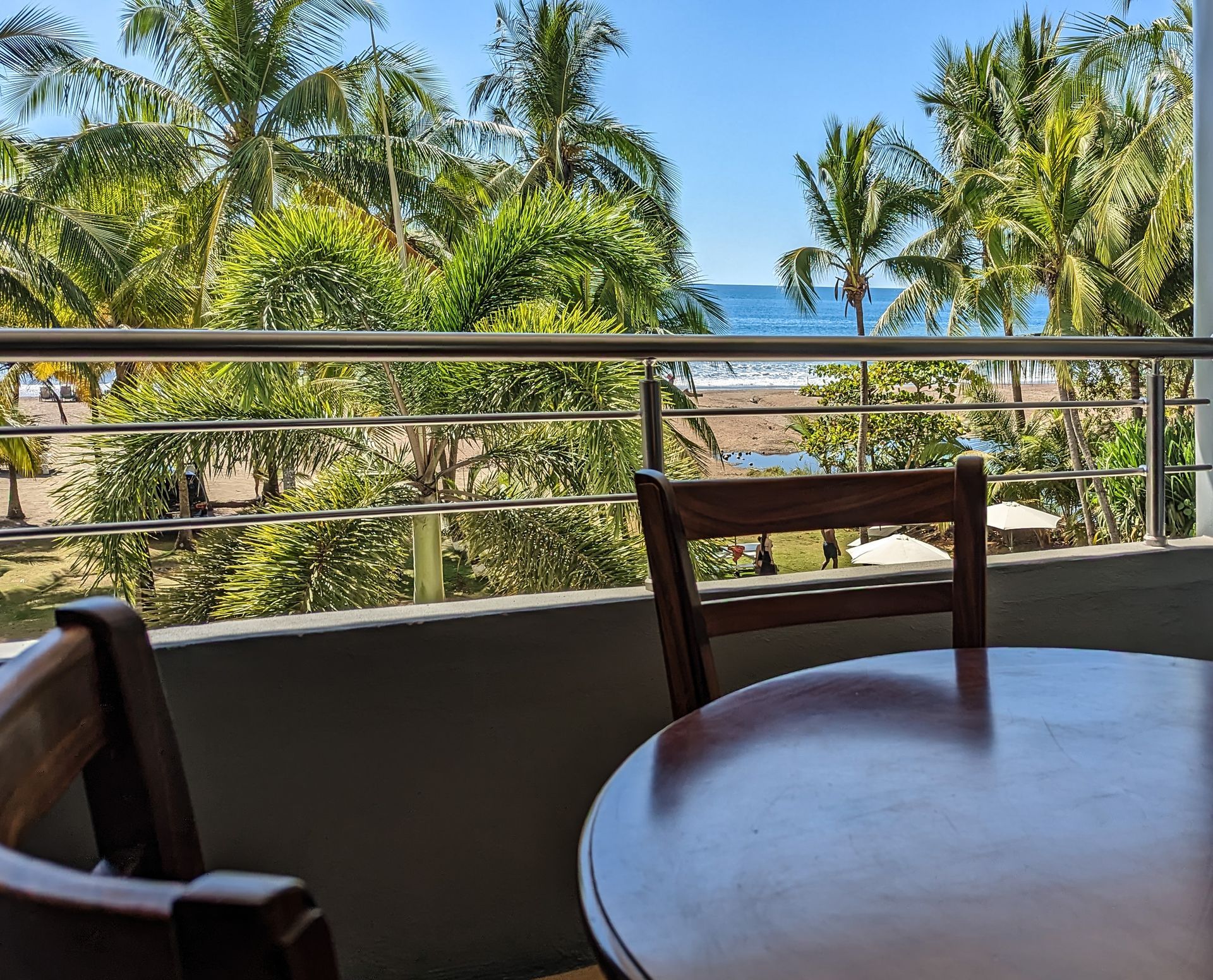 A table and chairs on a balcony overlooking the ocean.