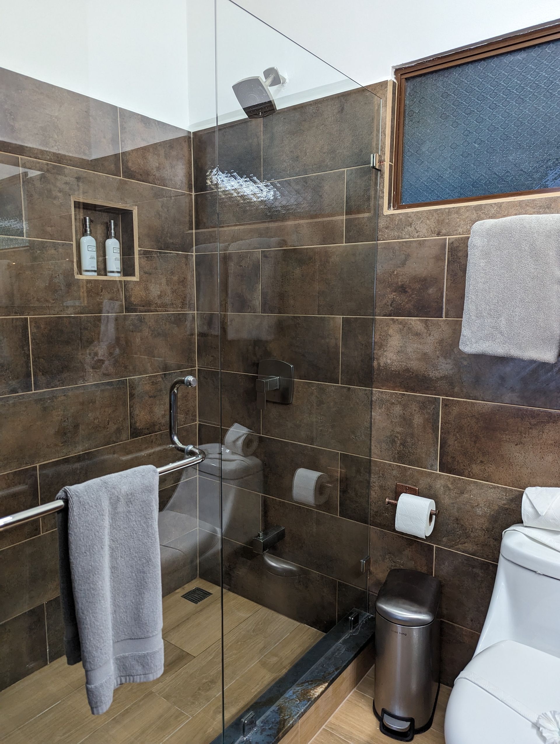 A bathroom with a toilet a shower and a trash can