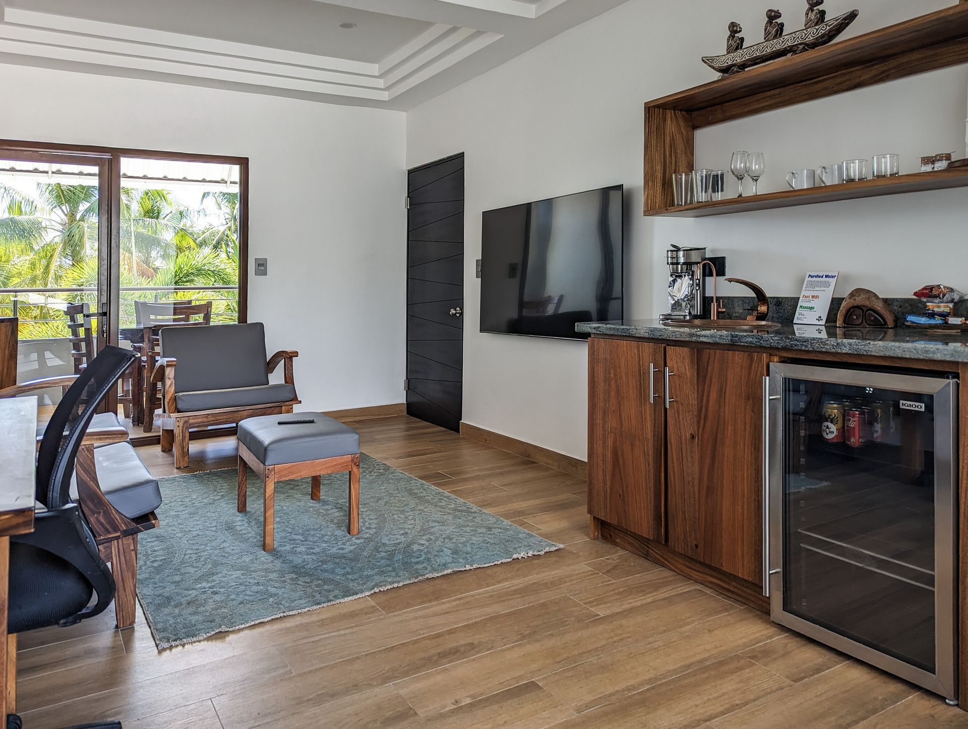 A living room with a refrigerator and a television on the wall.
