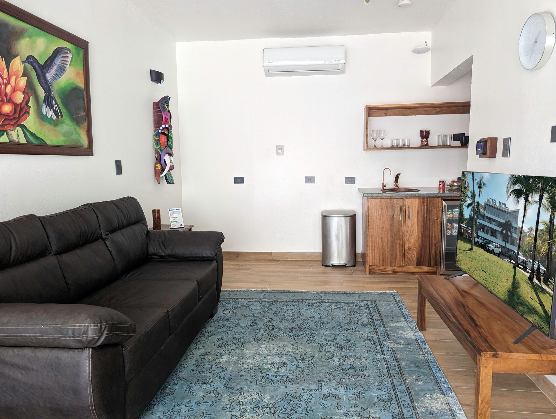 A living room with a couch , table , rug and painting on the wall.