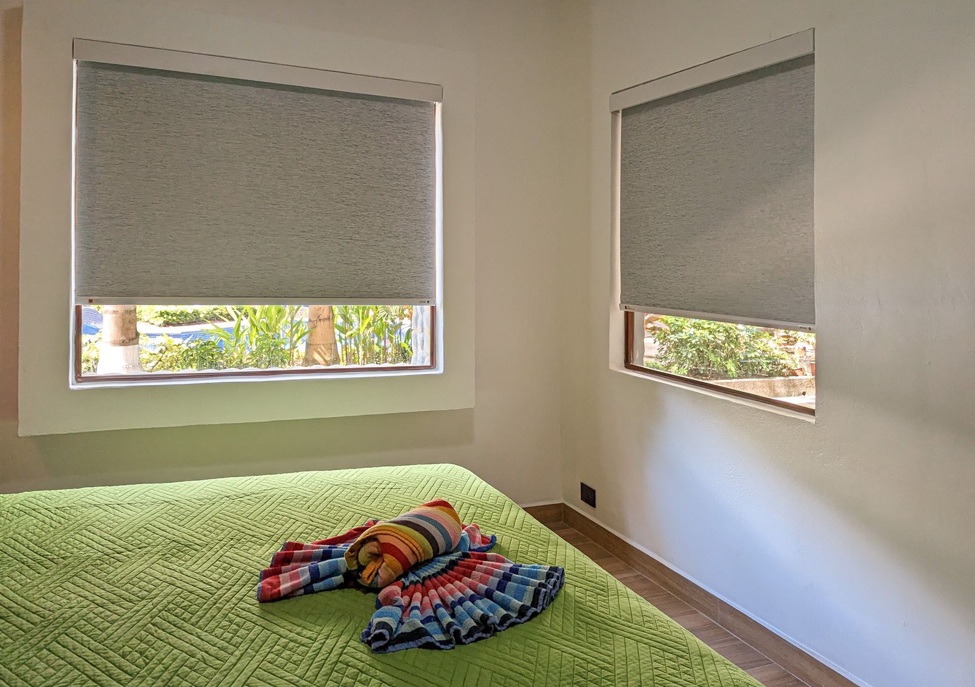 A bedroom with a bed and two windows with blinds on them.