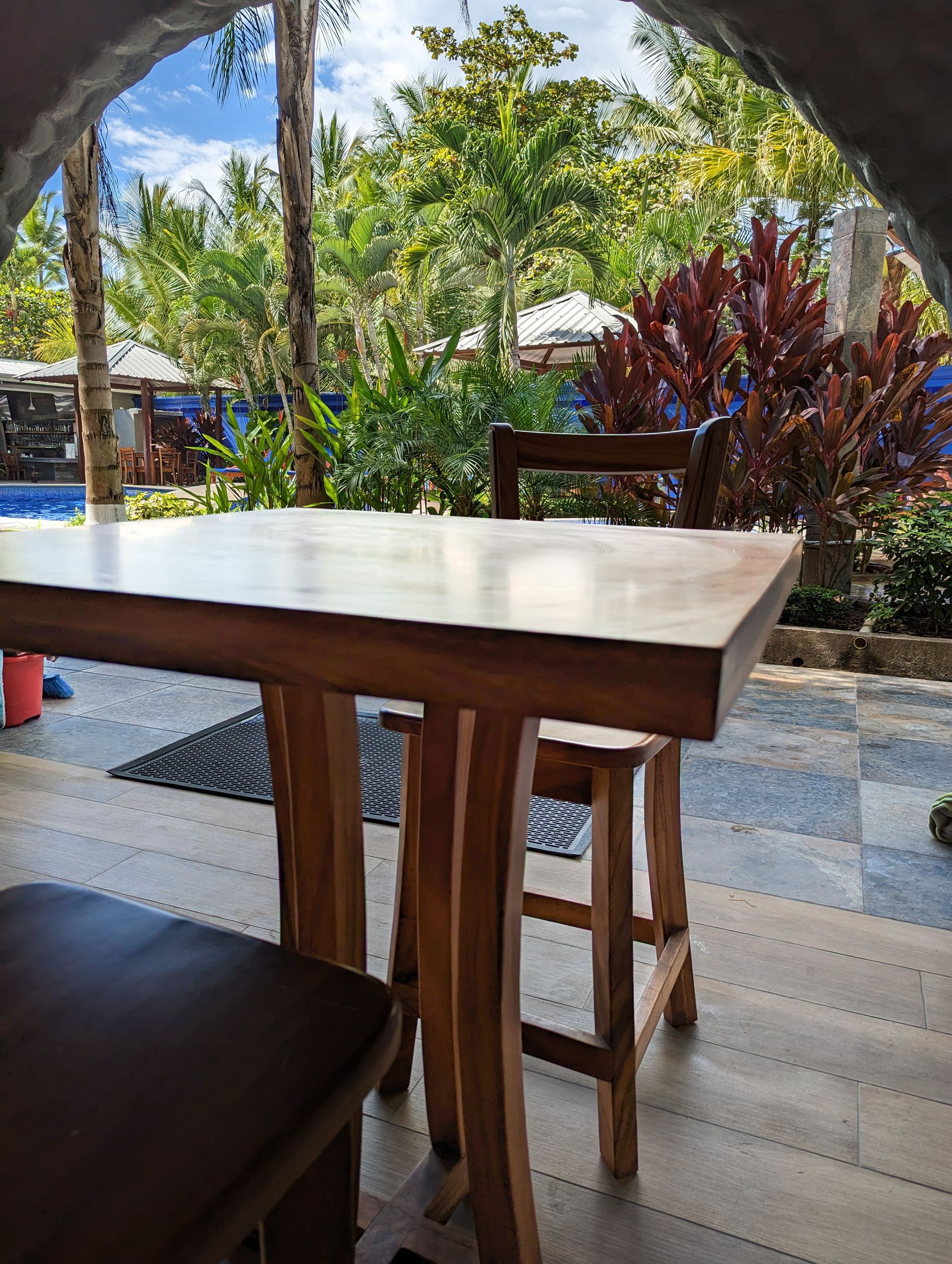 A wooden table and chairs are sitting on a patio next to a pool.
