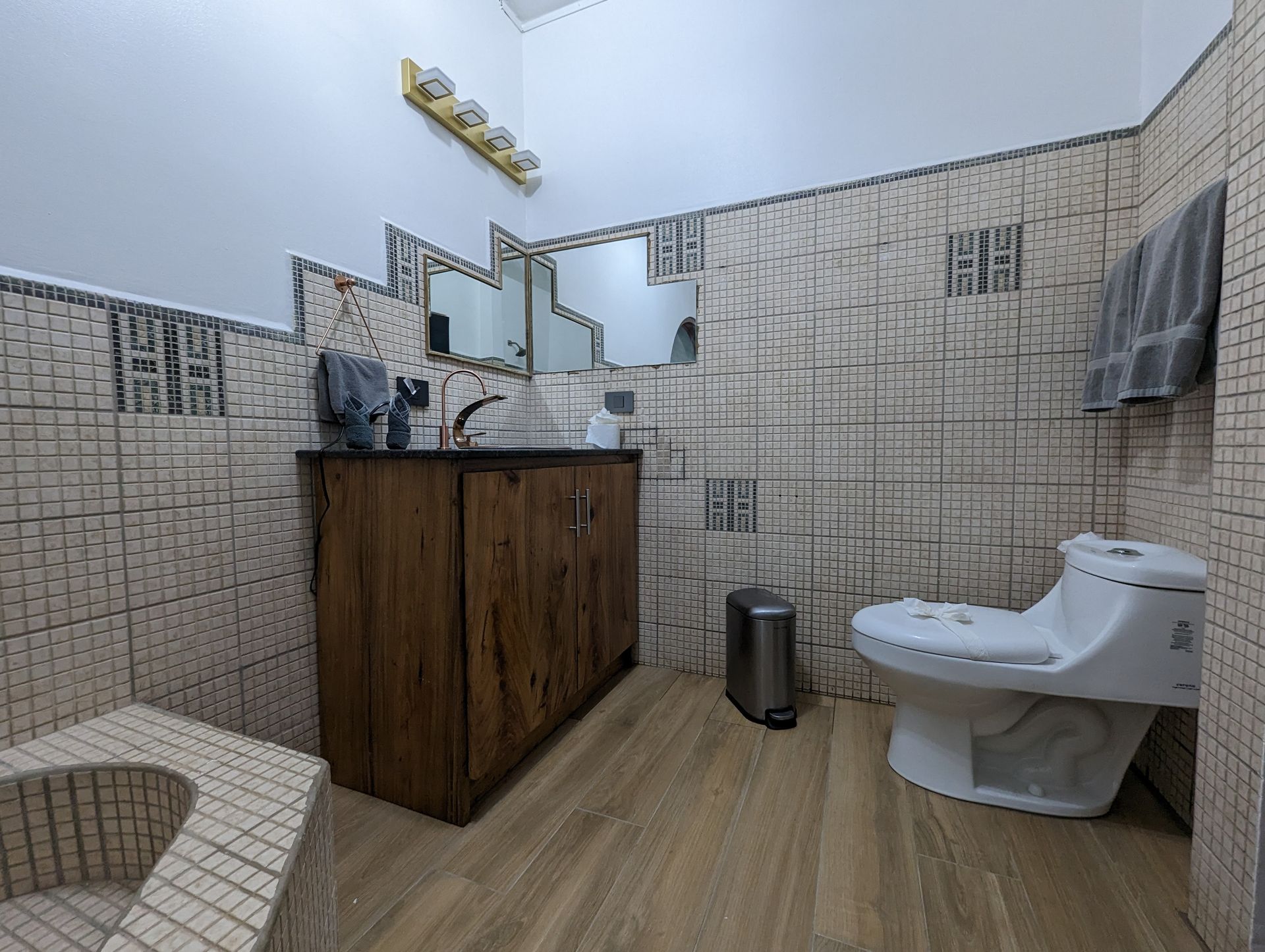 A bathroom with a toilet , sink and mirrors.