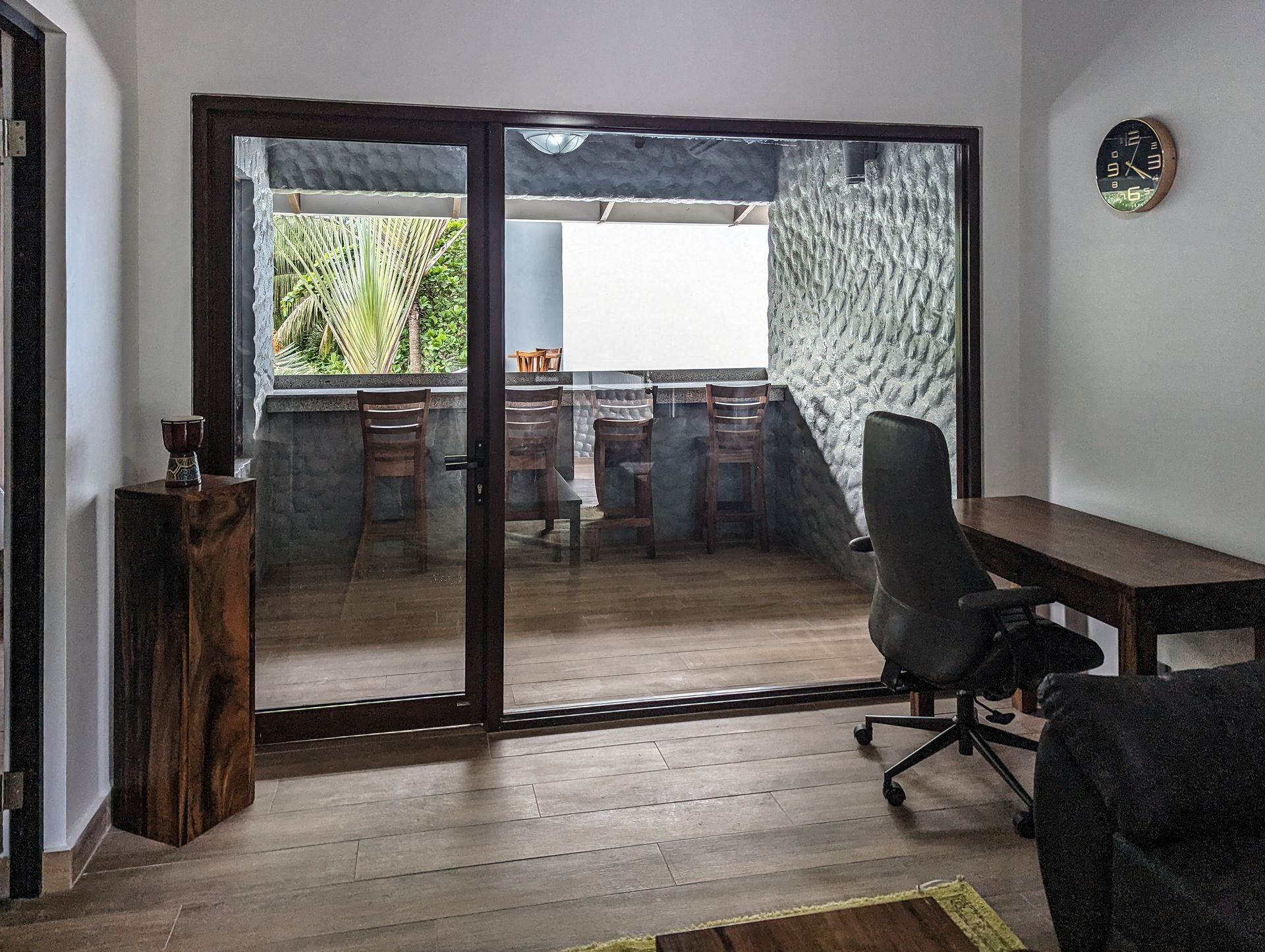 A living room with a desk , chair and sliding glass doors leading to a balcony.