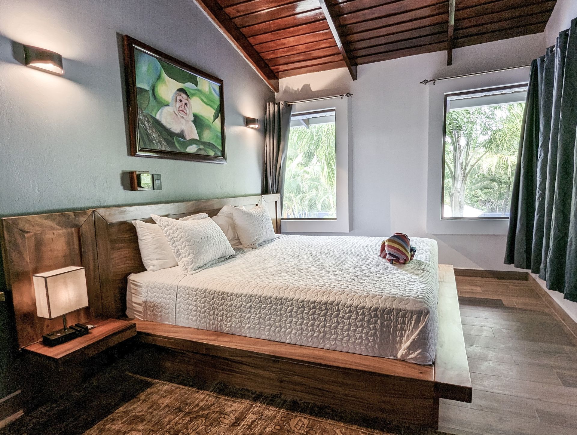 A bedroom with a large bed and a painting on the wall.
