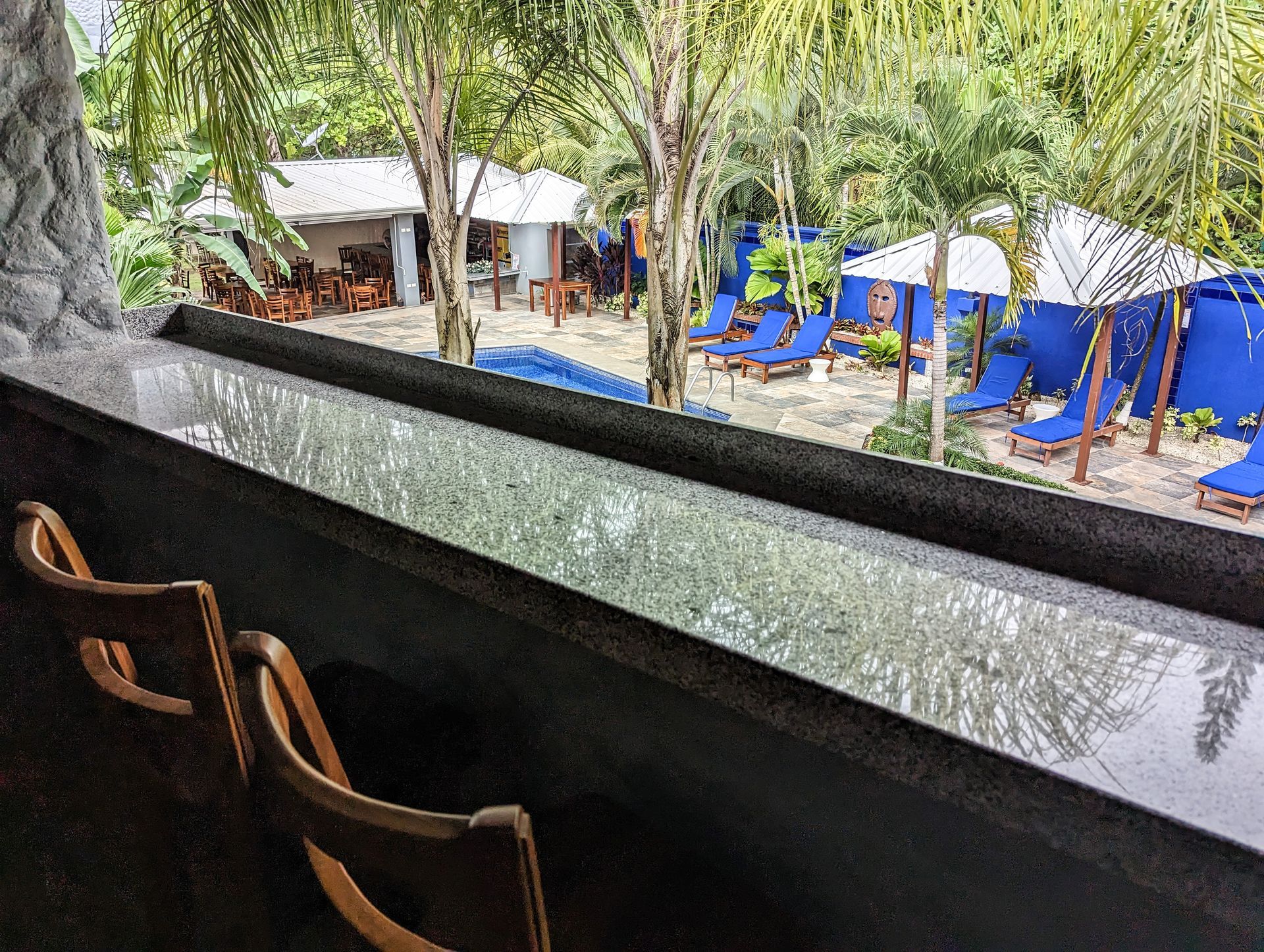 A view of a beach from a balcony with chairs and umbrellas.