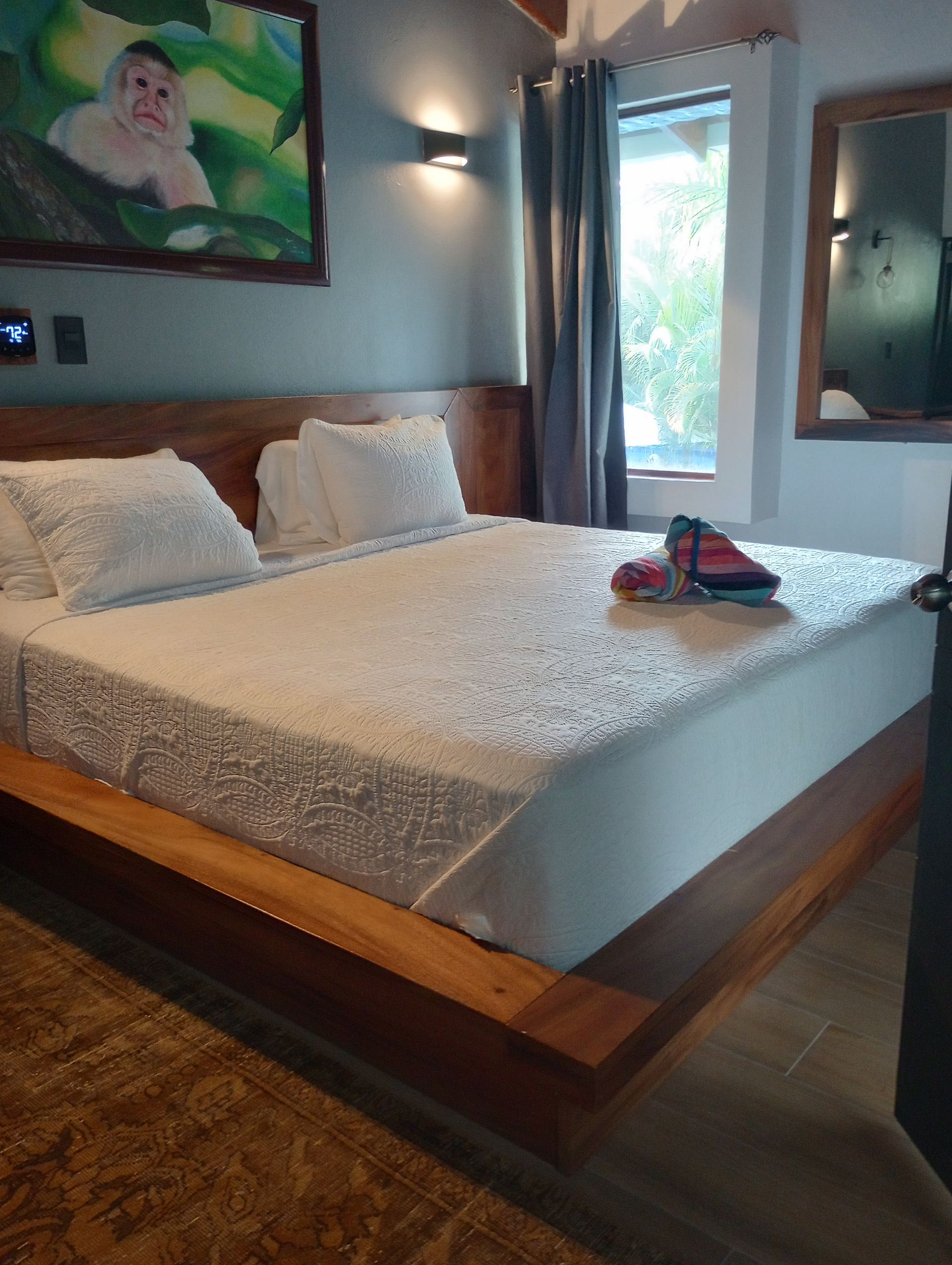 A bedroom with a large bed and a painting on the wall