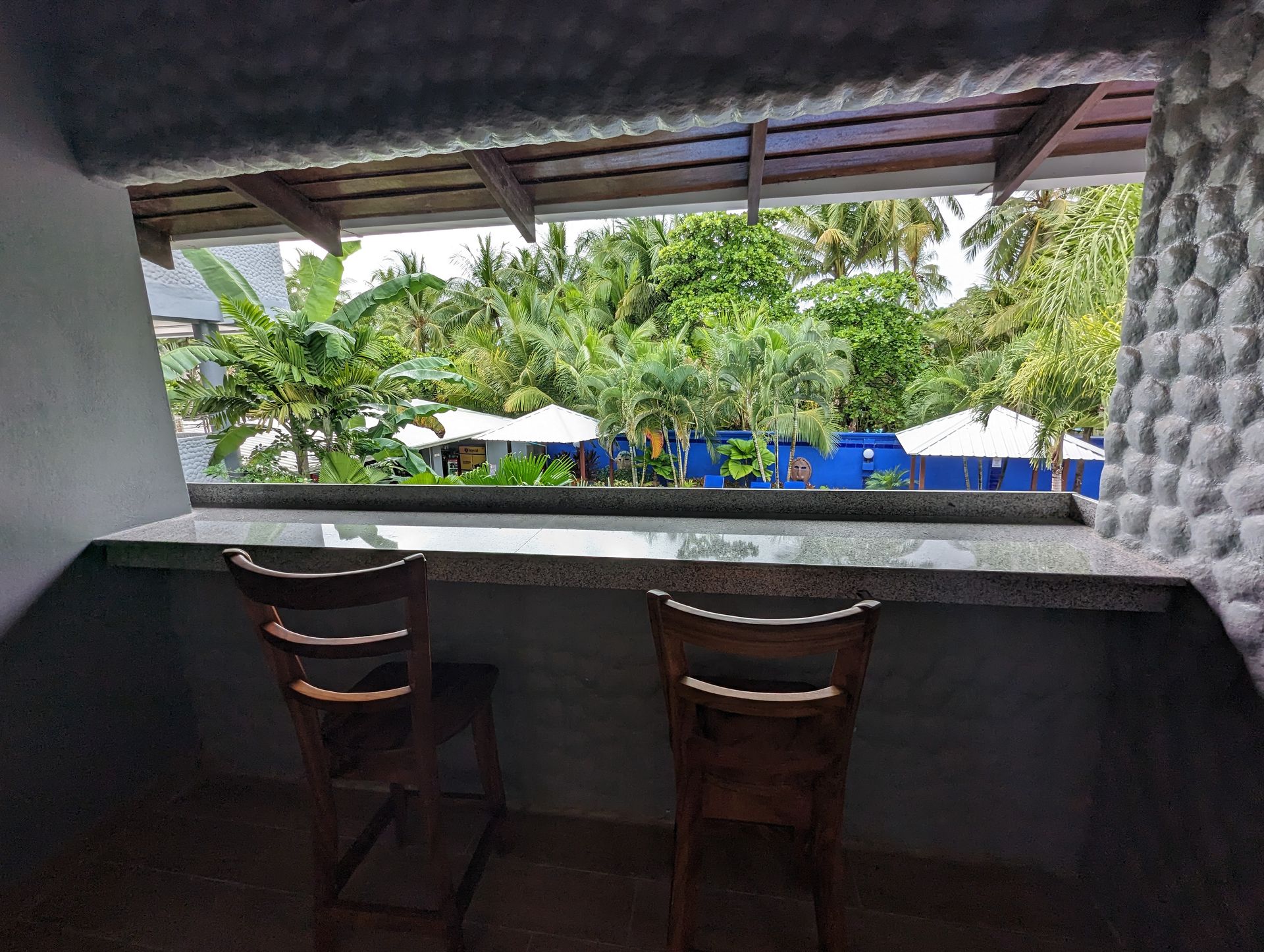 Two chairs are sitting in front of a window overlooking a lush green forest.