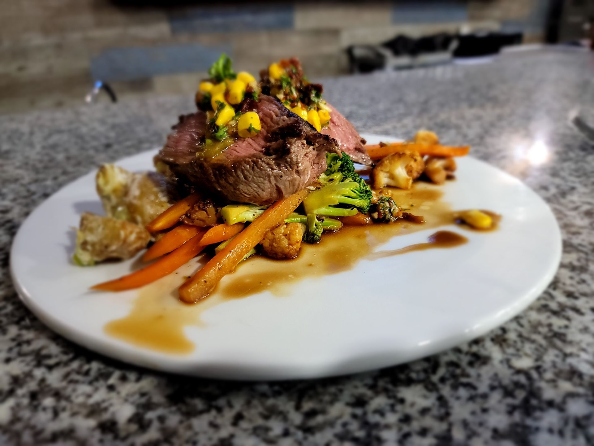 A white plate topped with meat and vegetables on a table.