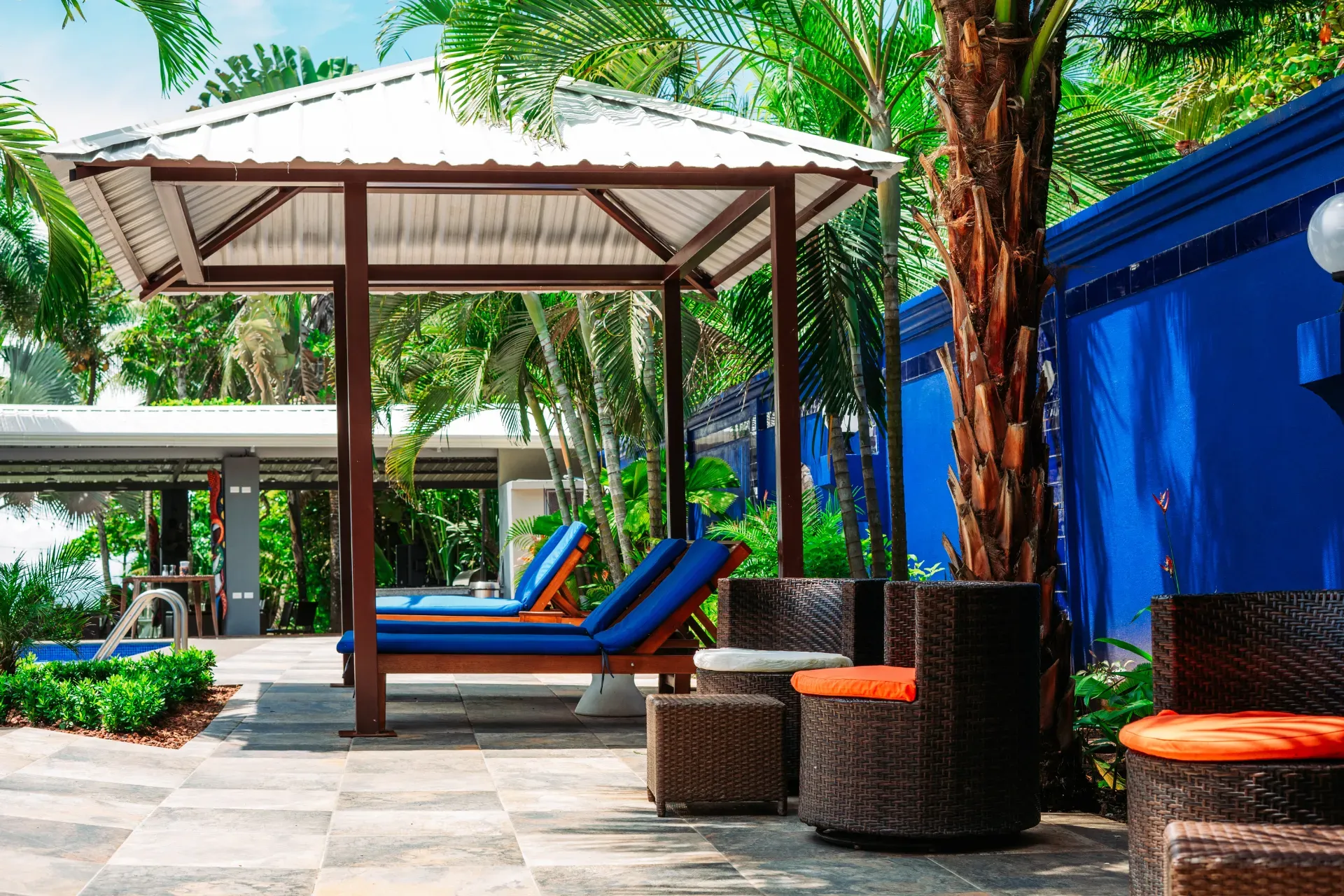 A gazebo with blue chairs and wicker furniture in front of a blue building.