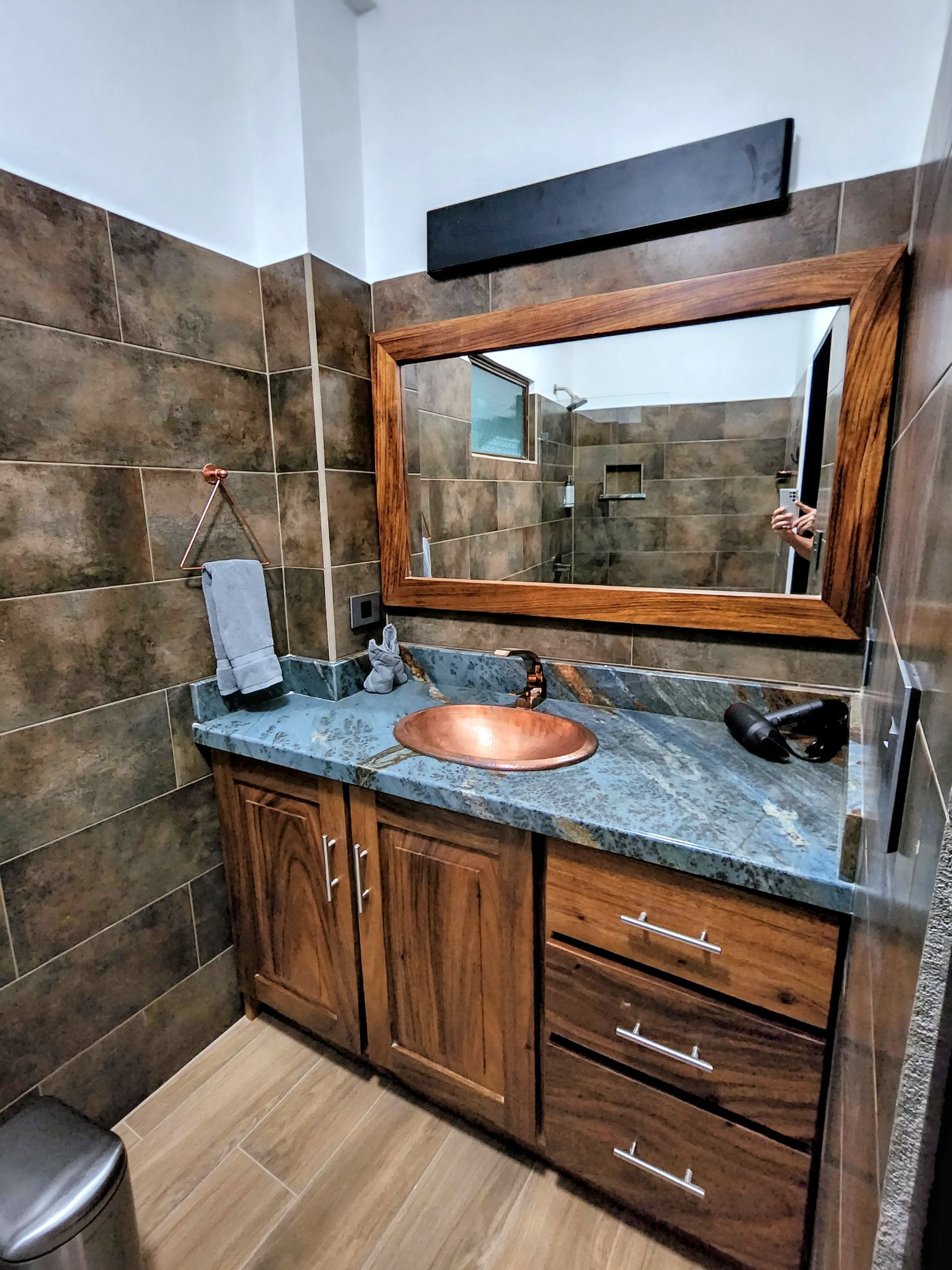 A bathroom with a sink , mirror and wooden cabinets.