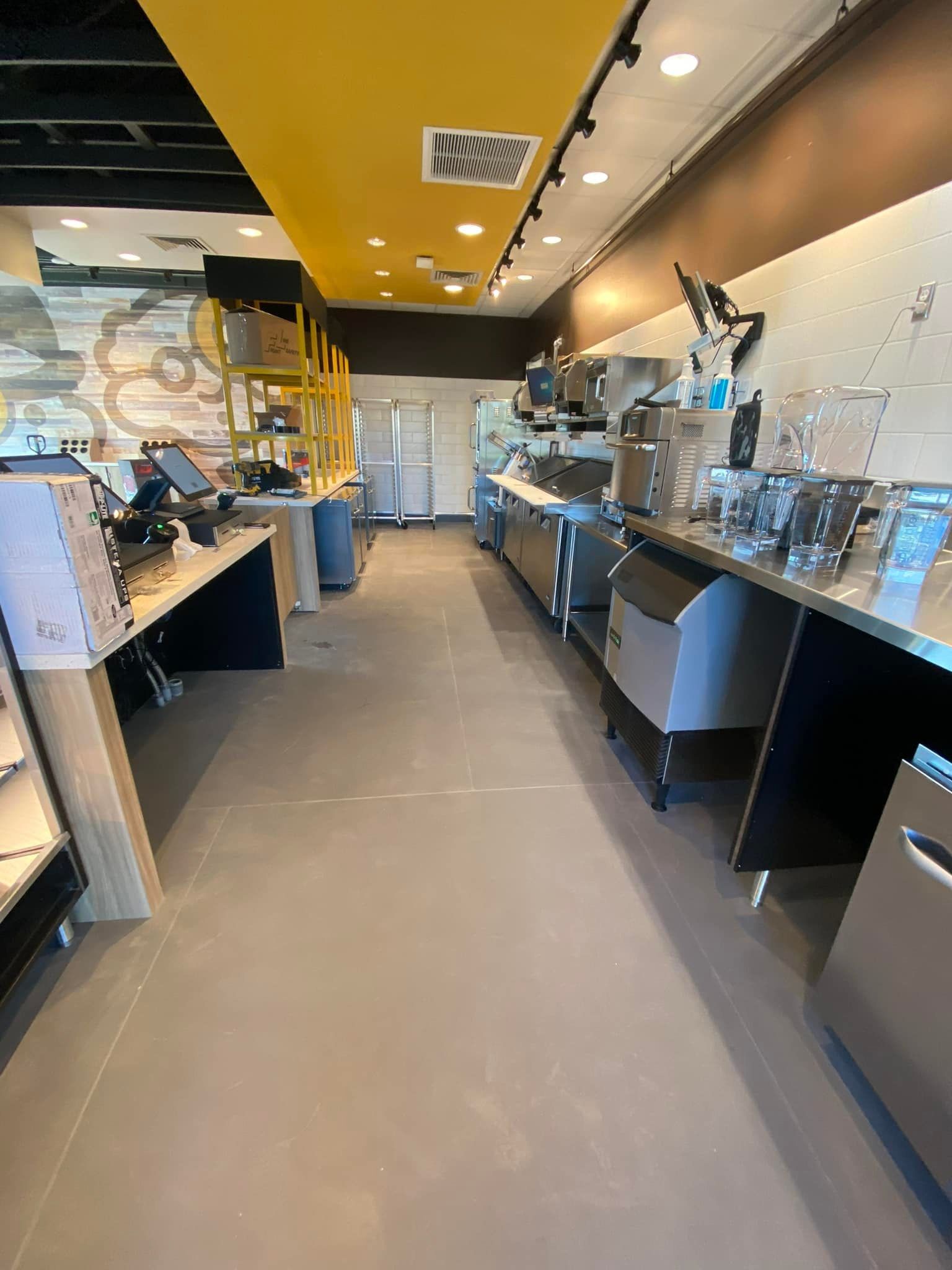 Interior of a brightly lit commercial kitchen with stainless steel counters and equipment.