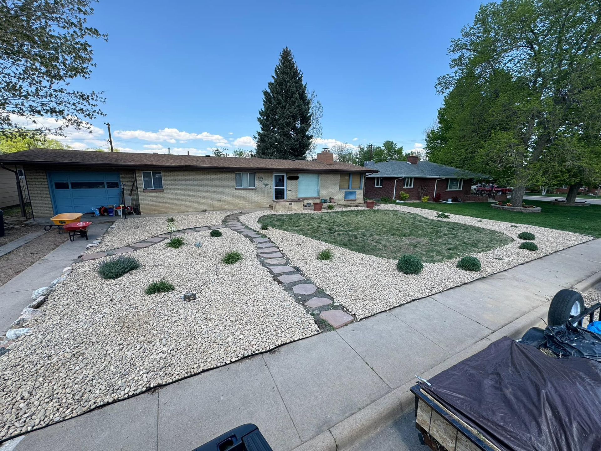 A single-story brick house with a xeriscape front yard and a light blue garage door.