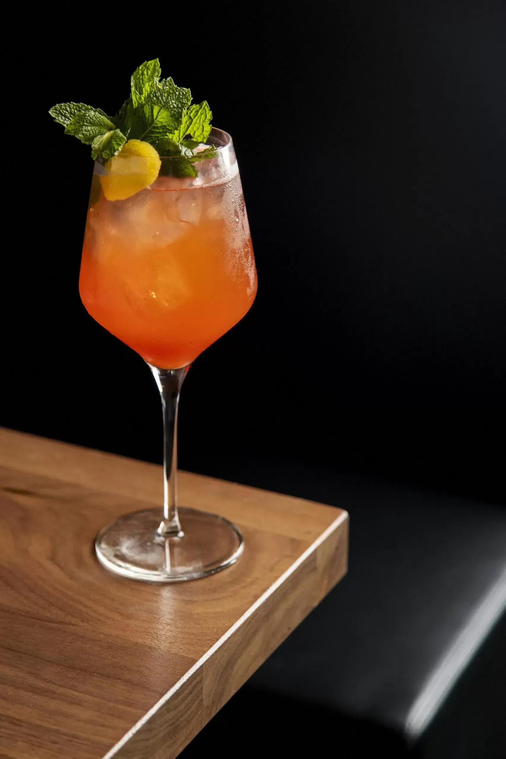 A close up of a drink in a wine glass on a table.