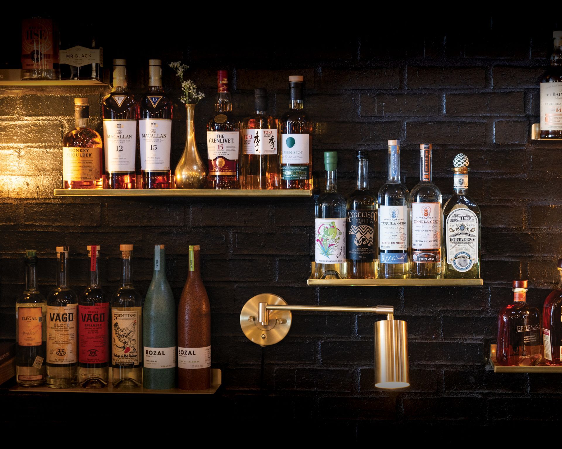 Bottles of alcohol are lined up on shelves in a dark room