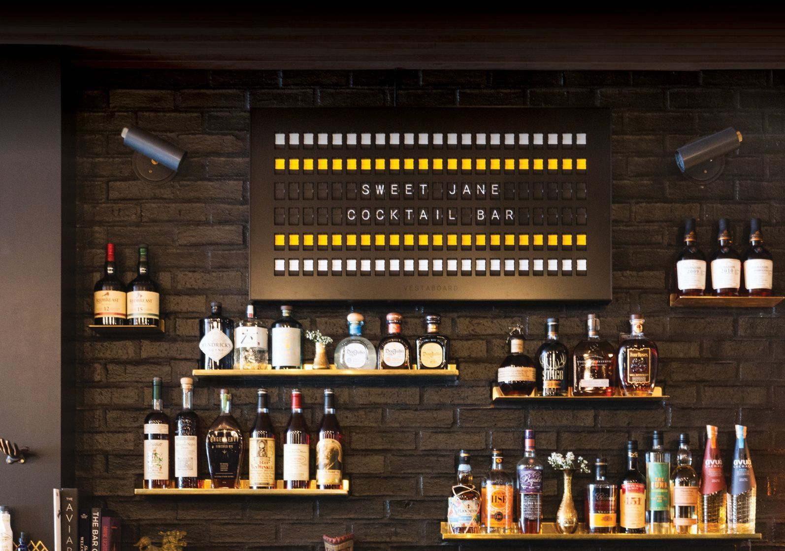 A brick wall with a sign that says sweet jane cocktail bar