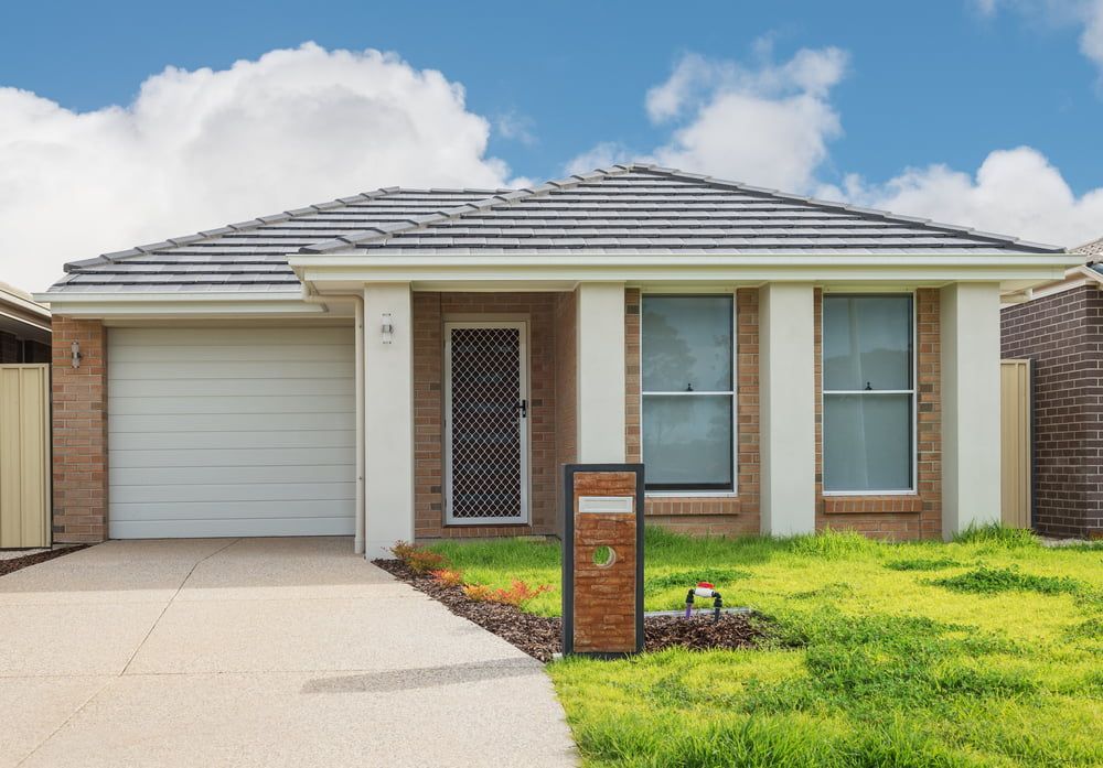 A Small Brick House with A White Garage Door — MJ Watson Construction and Maintenance in Wagga Wagga, NSW