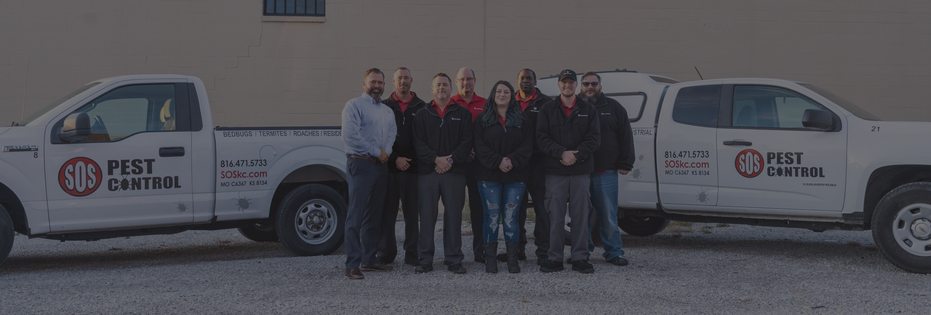 SOS Pest Control technicians and team of Kansas City are posing as a group by the building. They can exterminate bedbugs and termites from your business or home.