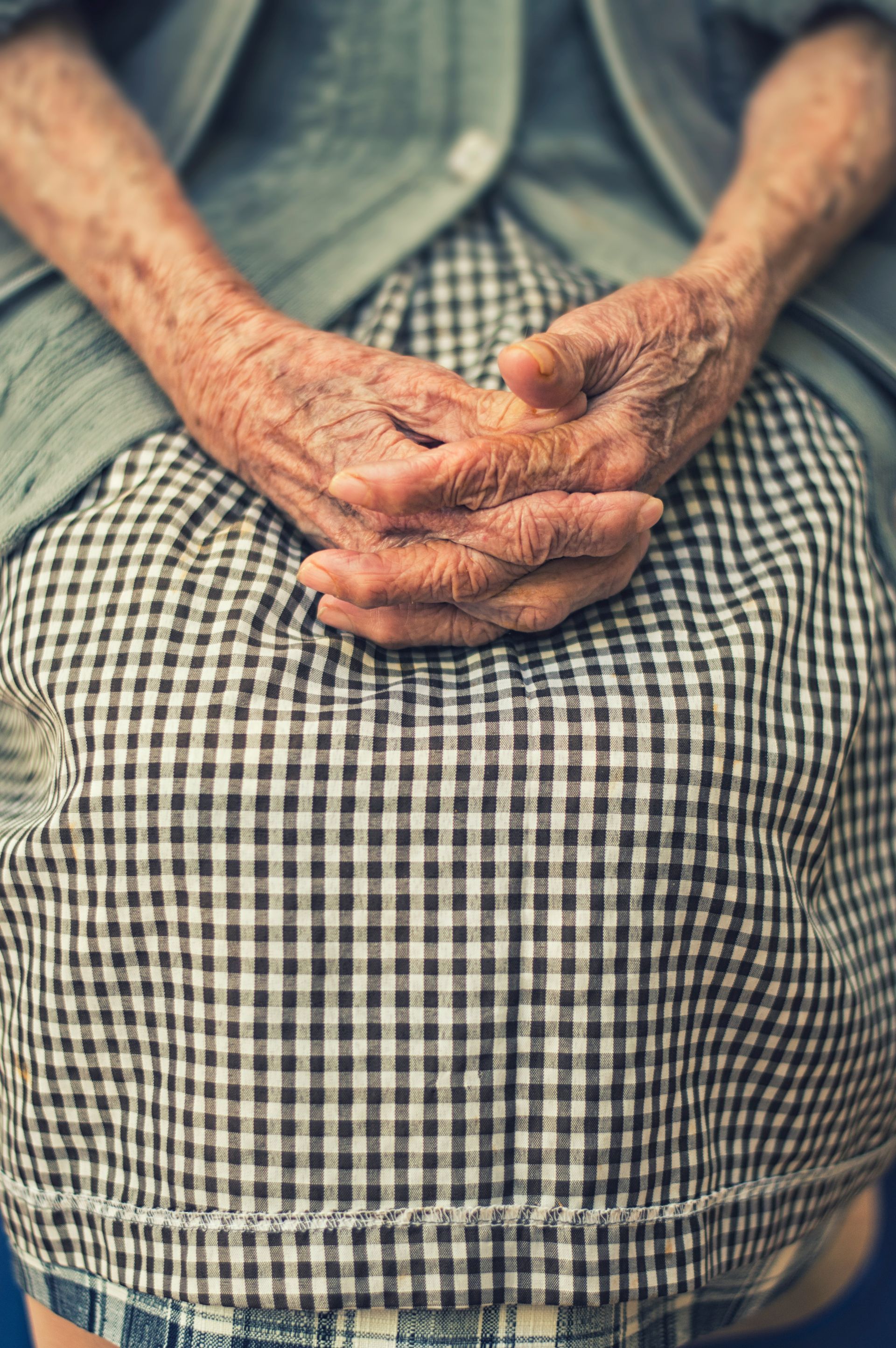 Old women sting down with hands together.