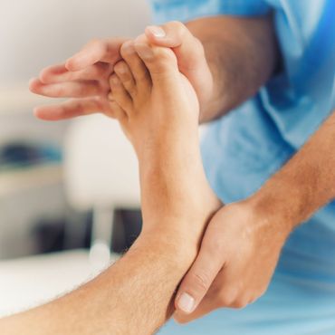 A doctor is holding a model of a foot in his hands.