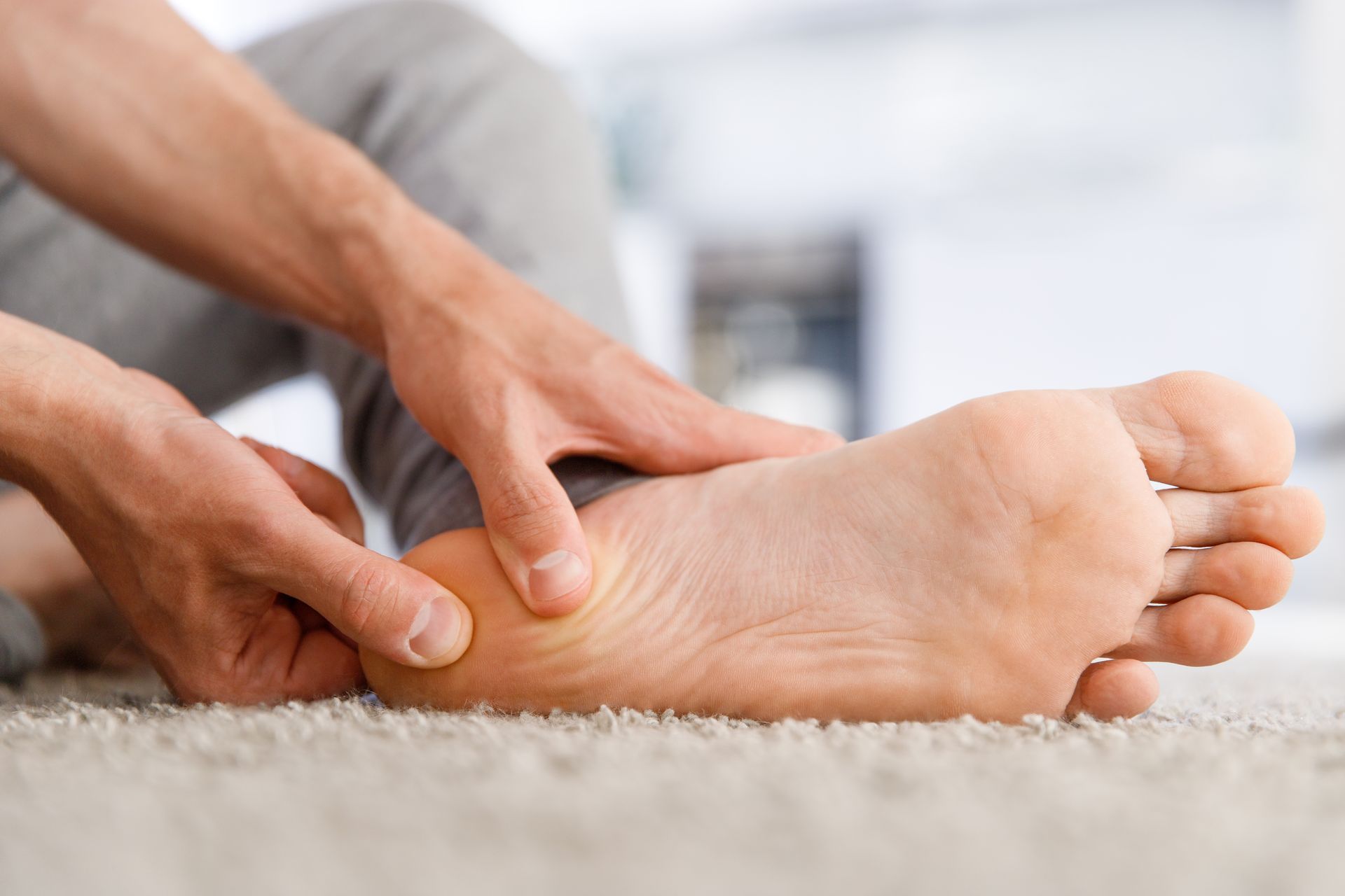 A woman is sitting on the ground with her legs crossed and stretching her feet.