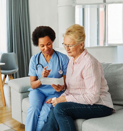 A doctor is standing next to an elderly woman in a wheelchair.