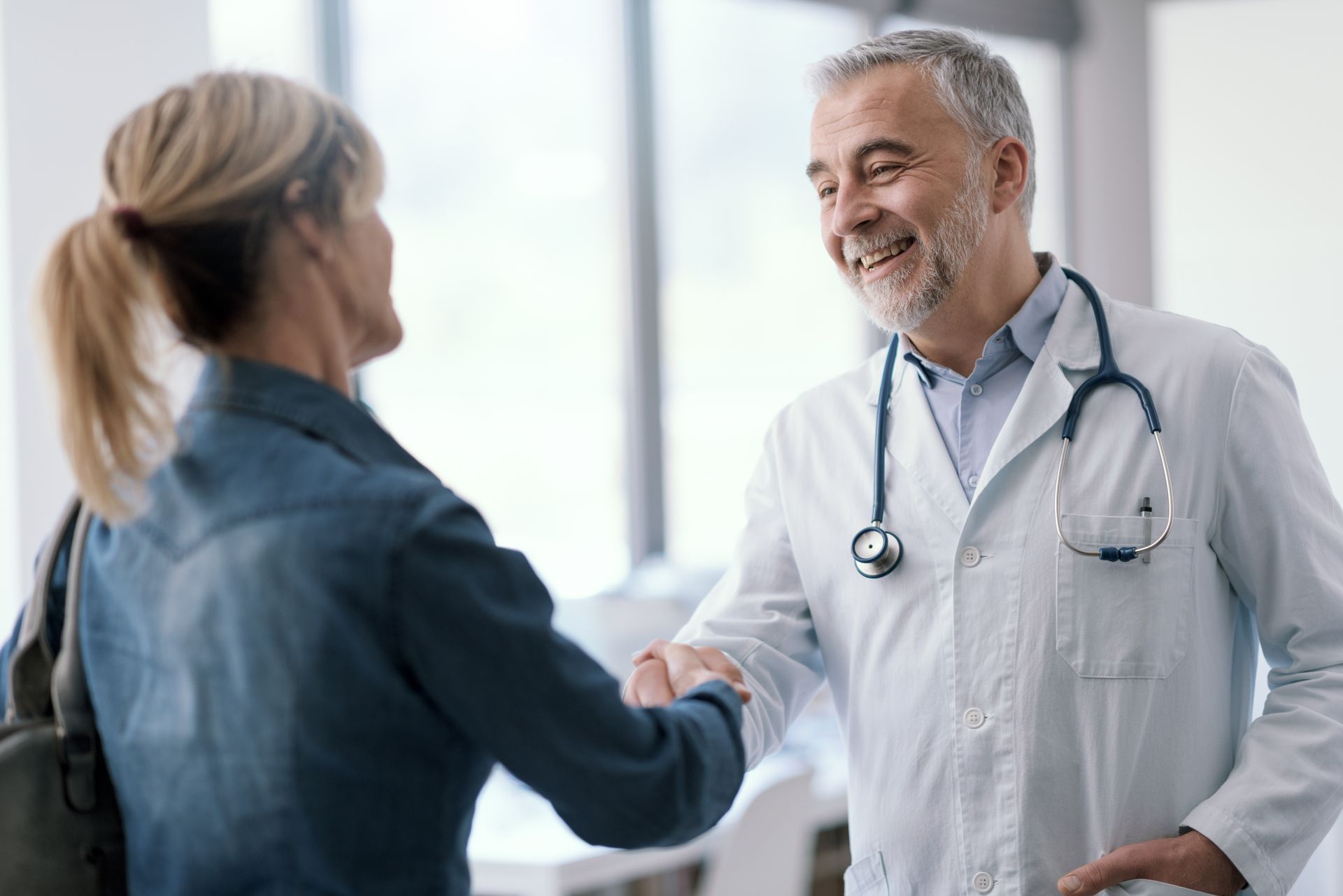 A smiling doctor in a lab coat with a stethoscope around his neck.