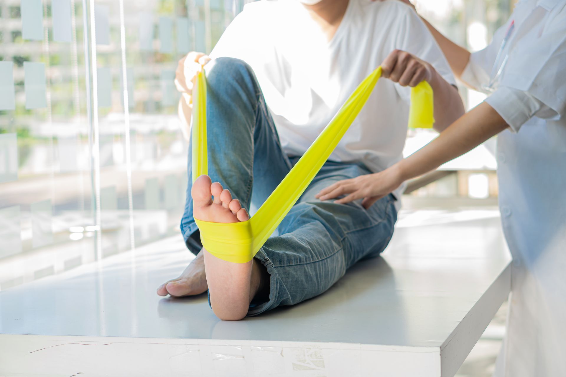 A woman is sitting on the ground with her legs crossed and stretching her feet.